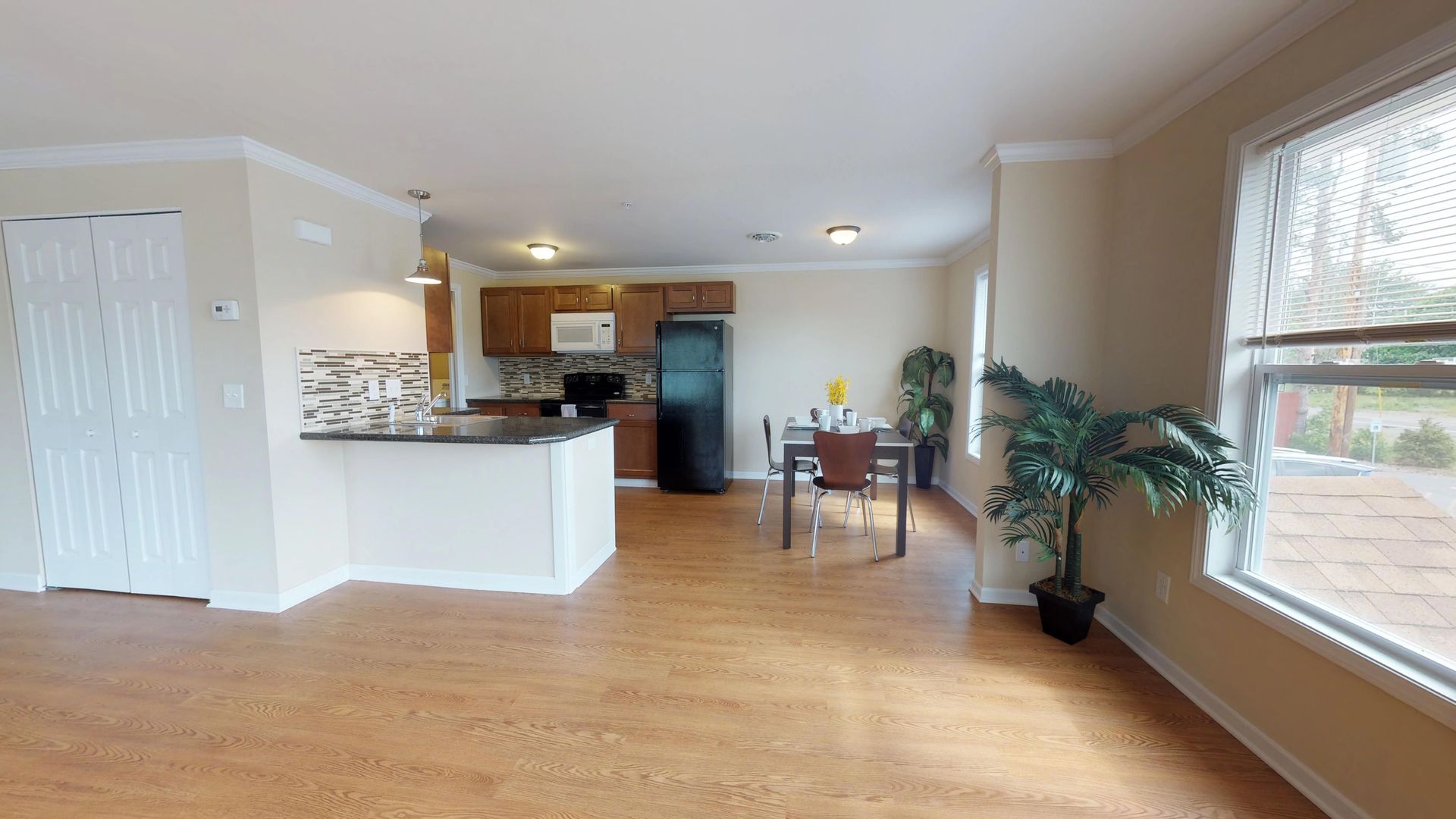 A living room with hardwood floors and a refrigerator in a house.