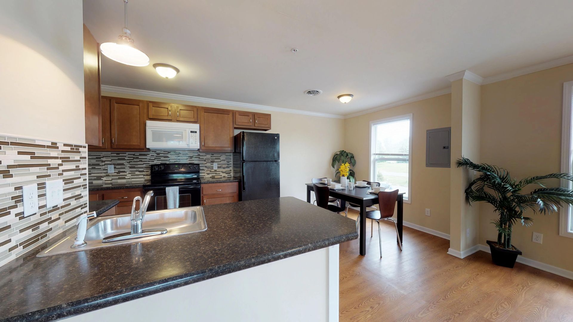 A kitchen with a black refrigerator and a sink
