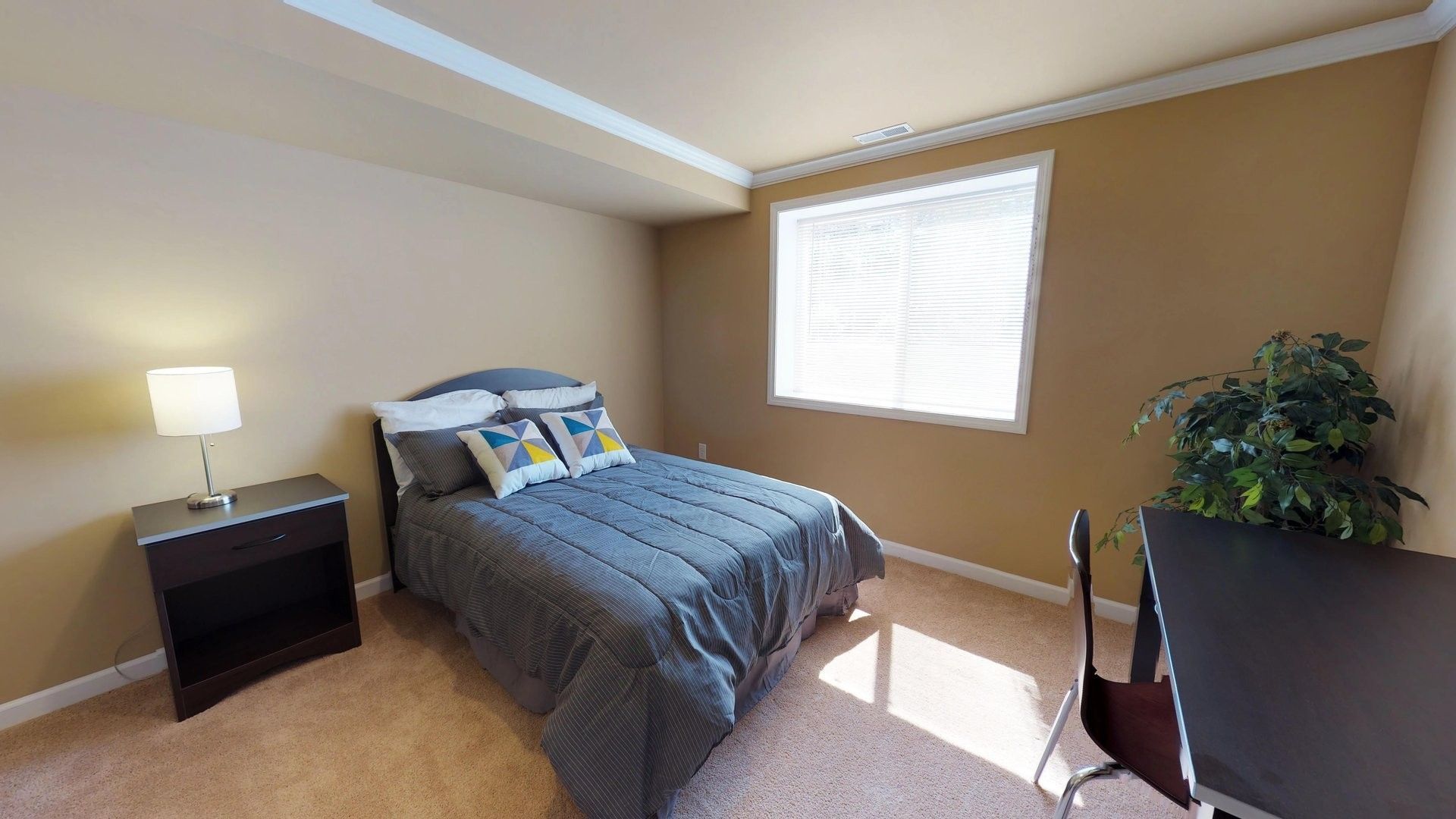 A bedroom with a bed , nightstand , desk and window.