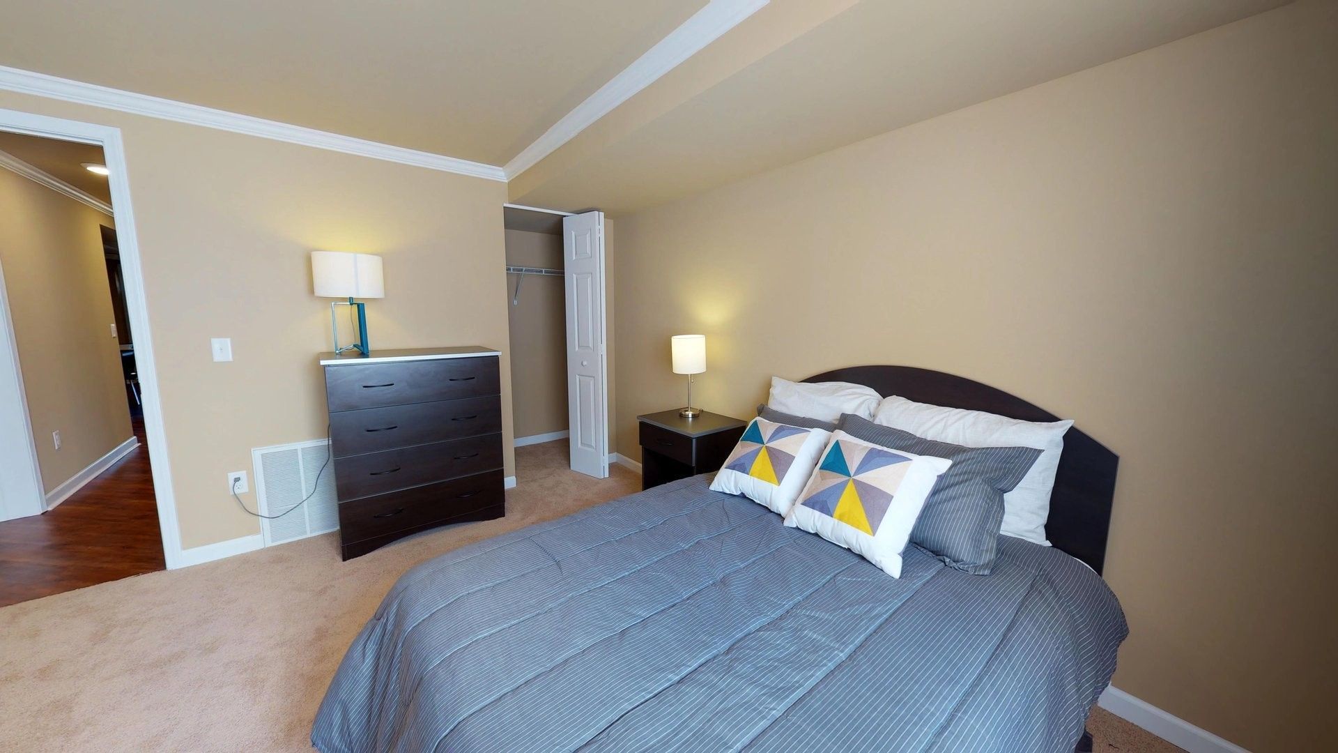 A bedroom with a bed , dresser , nightstand and lamp.