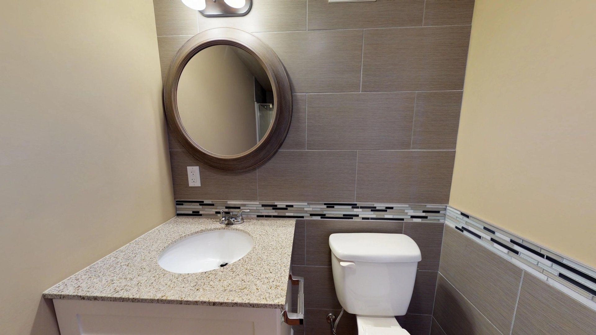 A bathroom with a toilet , sink and mirror.