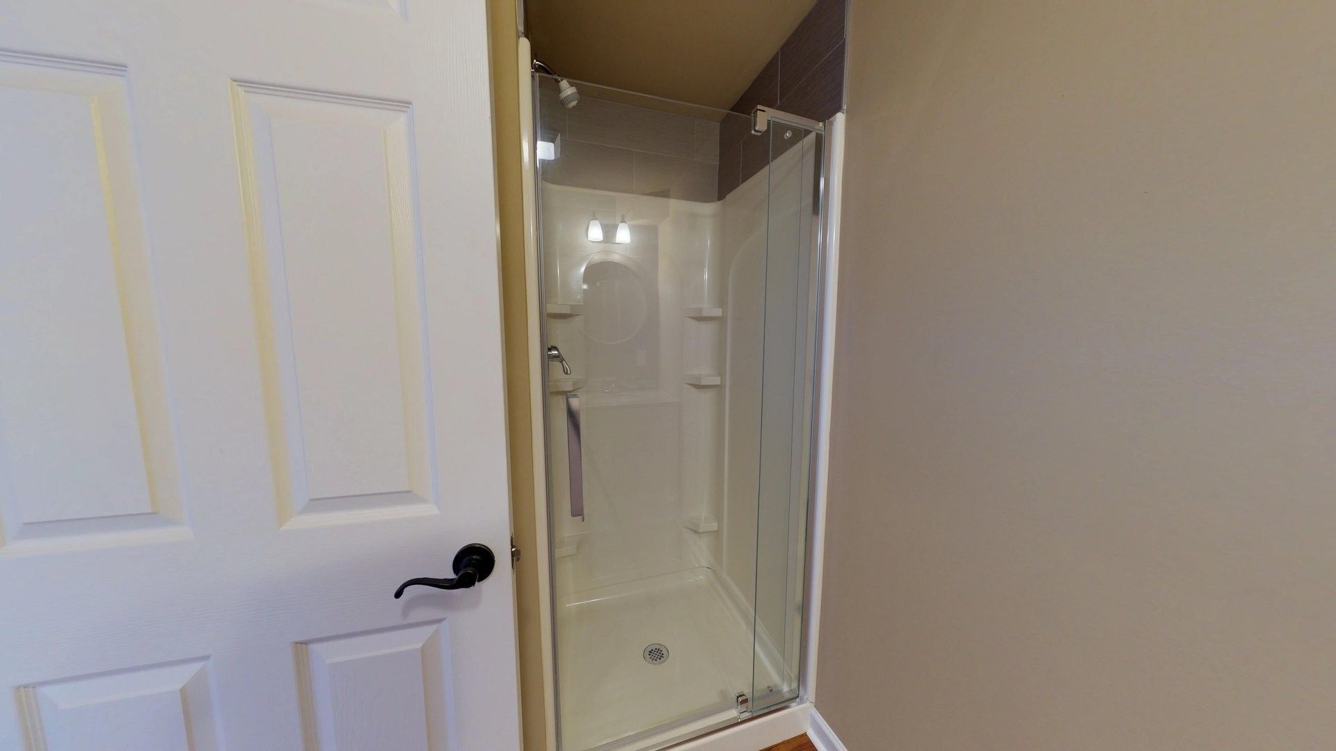 A bathroom with a walk in shower with a glass door.