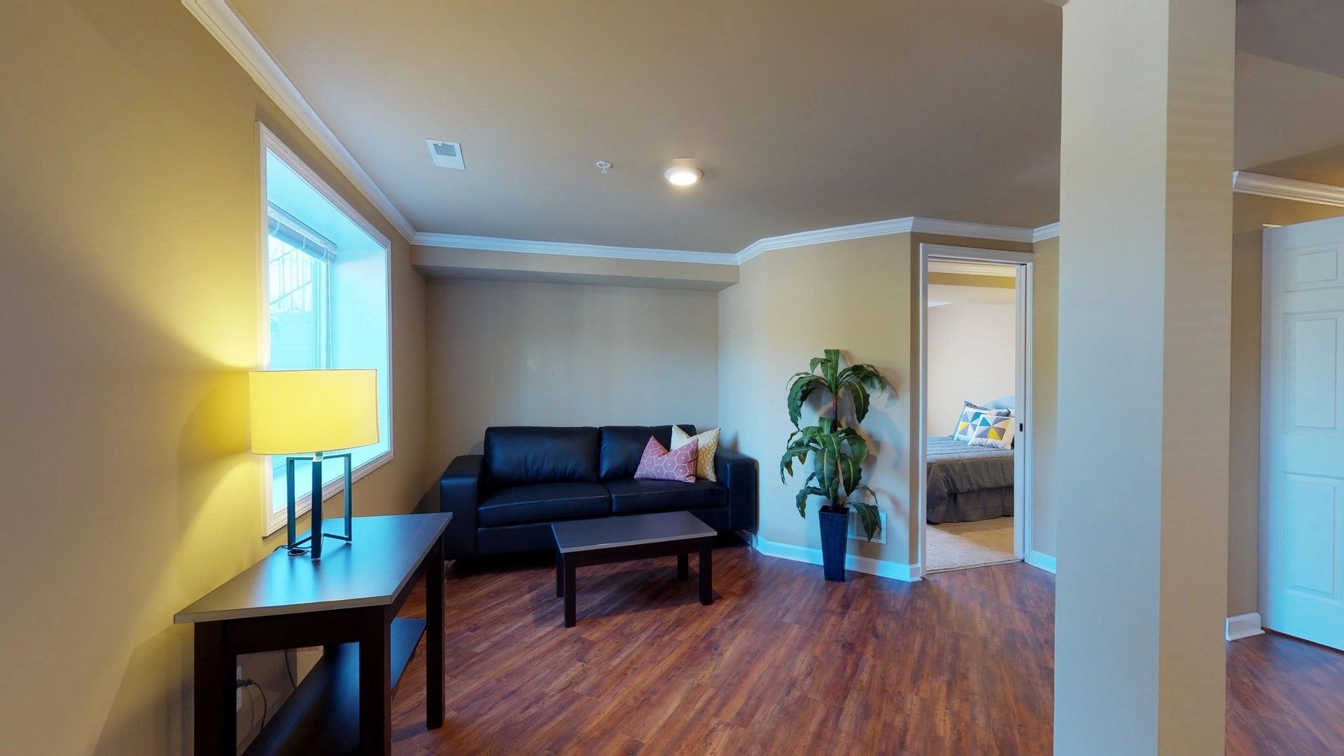 A living room with a couch , table , lamp and window.