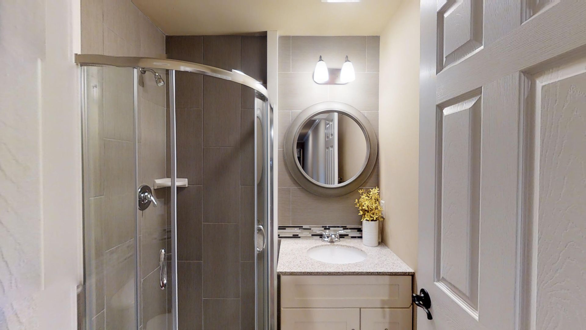 A bathroom with a sink , mirror and shower stall.