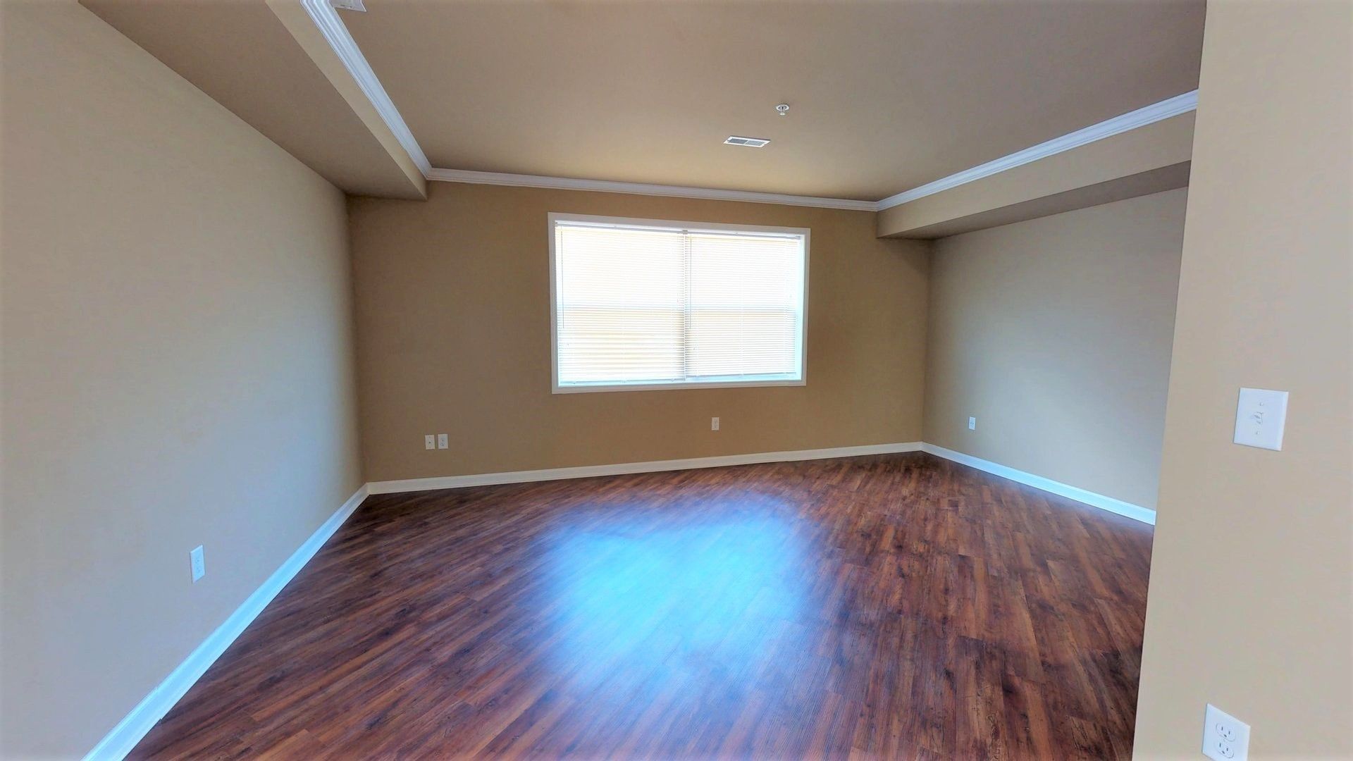 An empty living room with hardwood floors and a window.