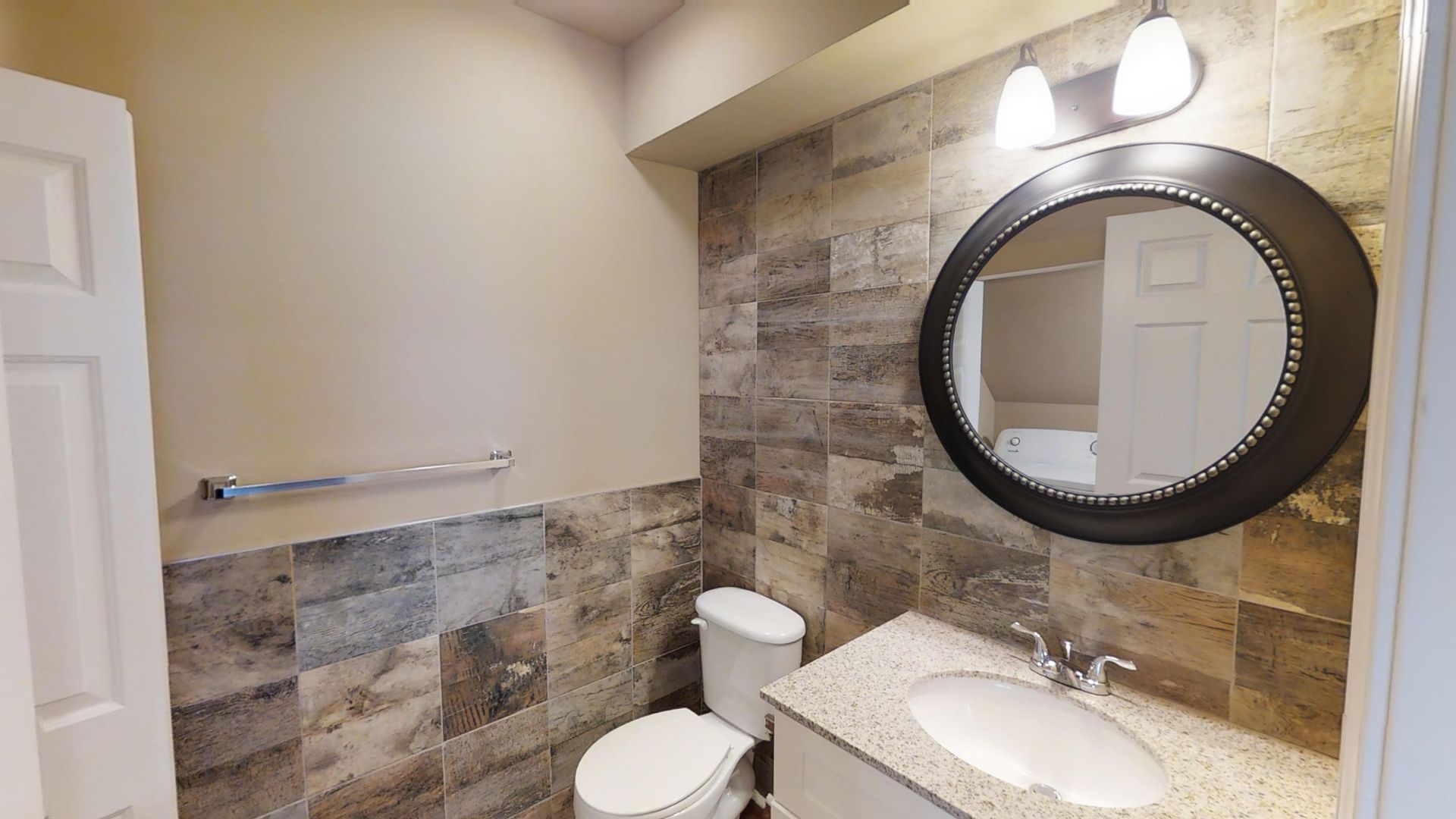 A bathroom with a toilet , sink and mirror.
