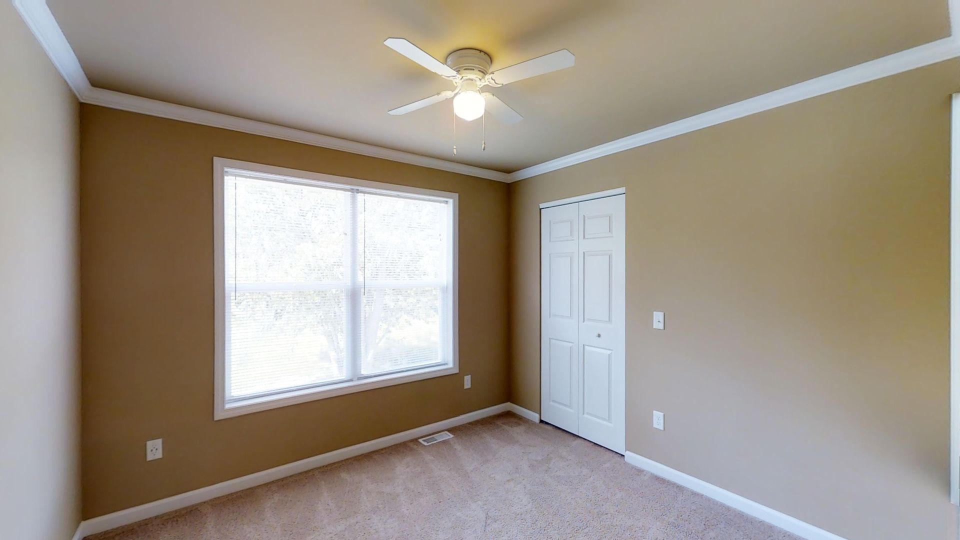 An empty bedroom with a ceiling fan and a window.