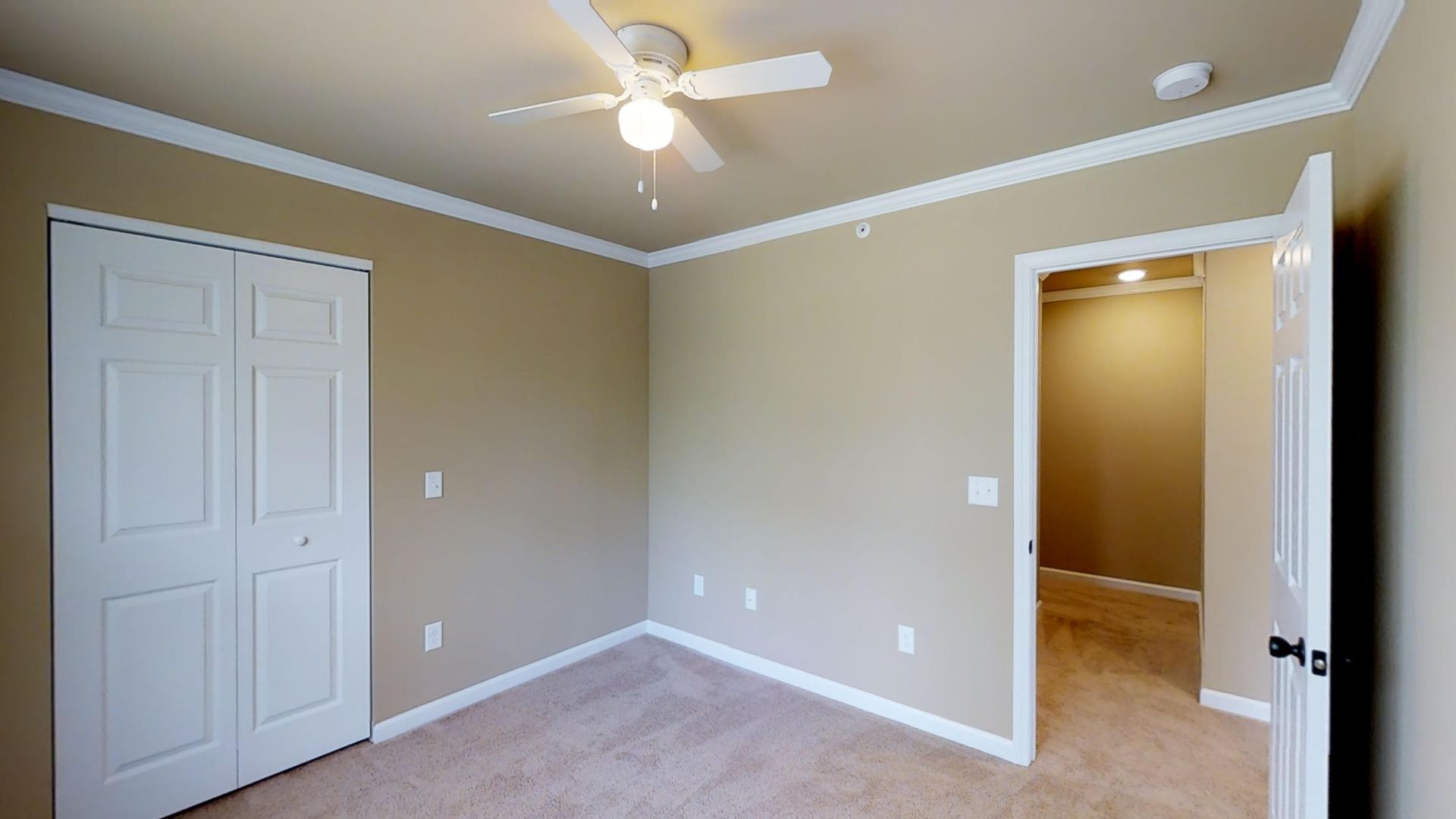 An empty bedroom with a ceiling fan and a walk in closet.