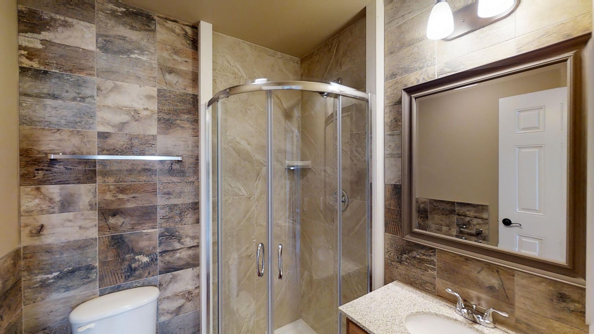 A bathroom with a toilet , sink , shower and mirror.