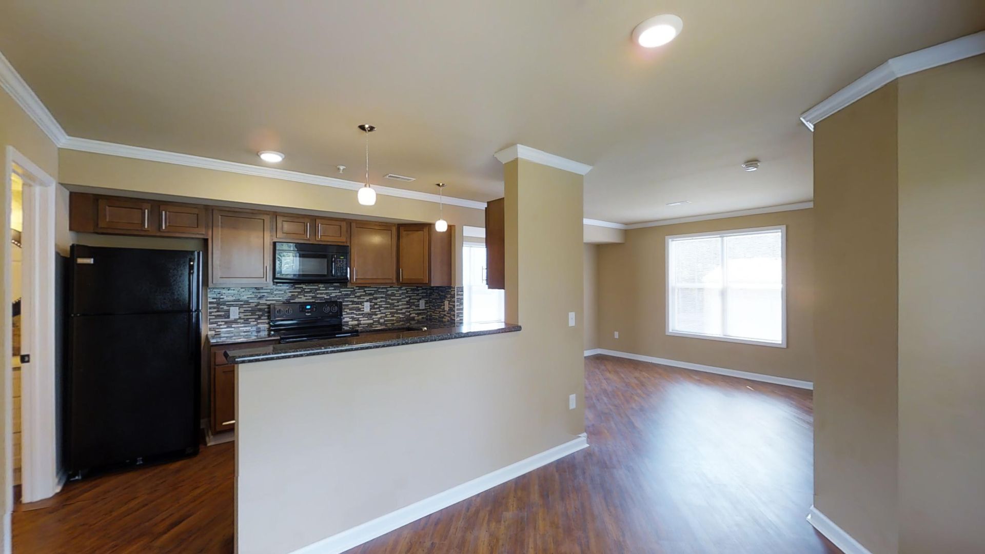 An empty apartment with a kitchen and a living room.