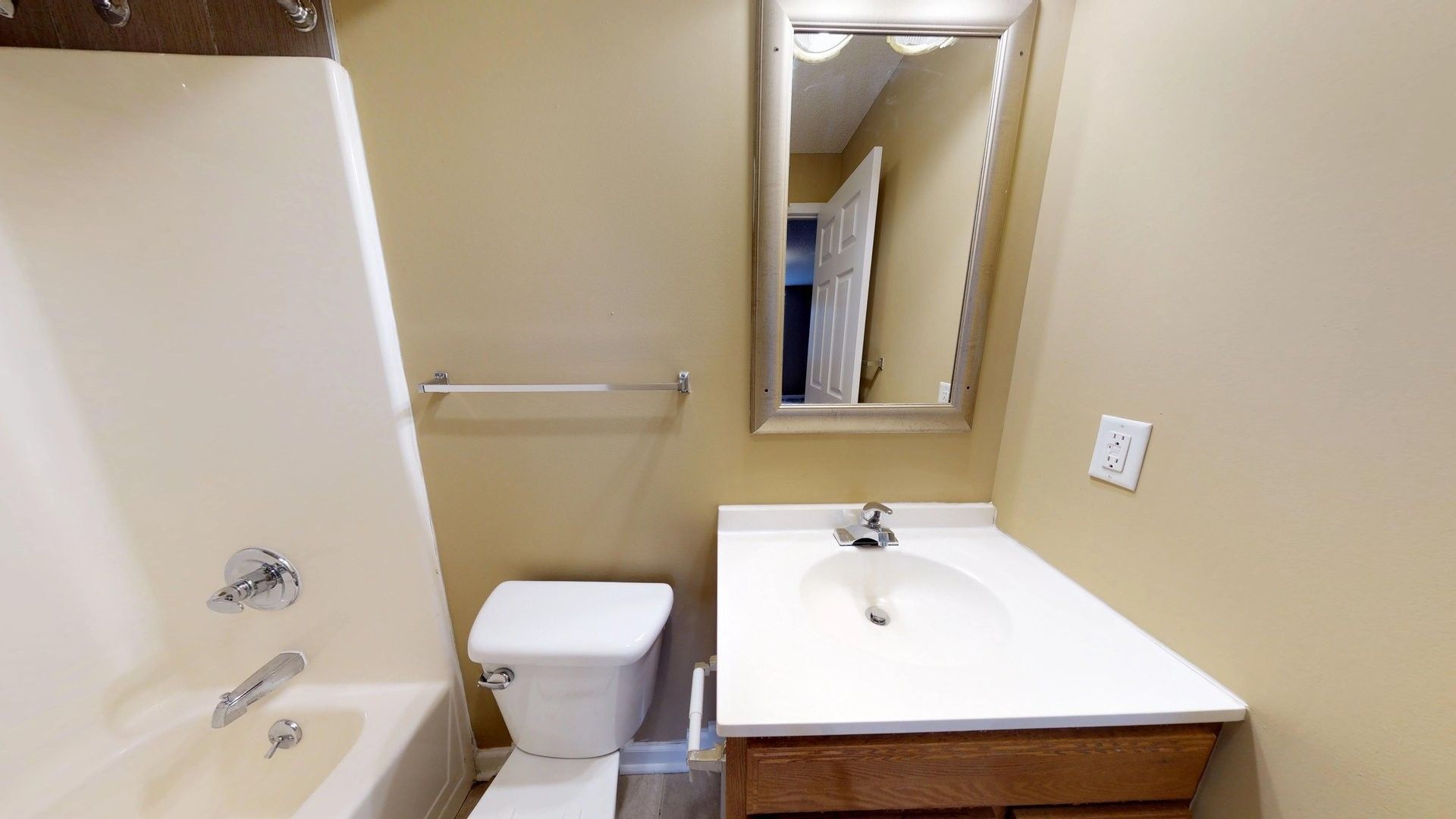 A bathroom with a toilet , sink , bathtub and mirror.