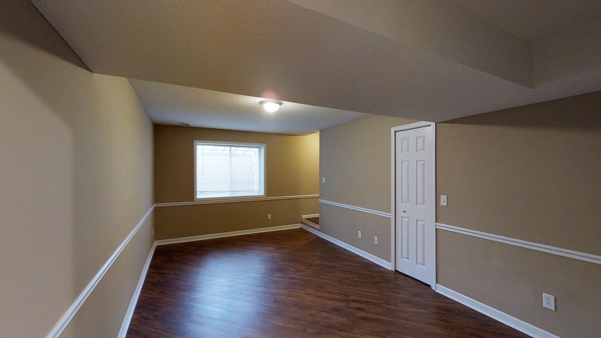An empty room with hardwood floors and a window.