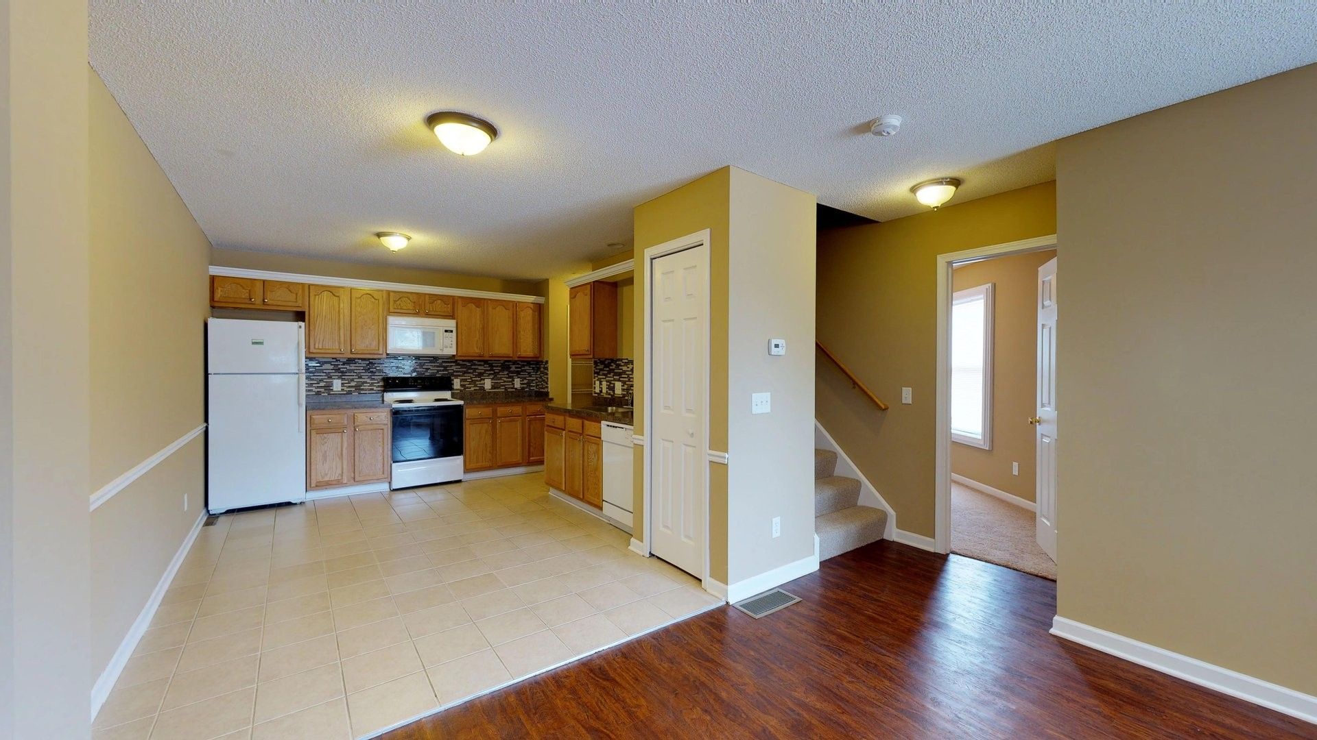 An empty house with a kitchen , living room , and stairs.