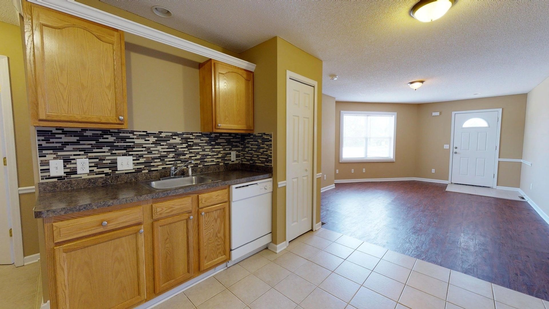 A kitchen with wooden cabinets , a sink , and a dishwasher.