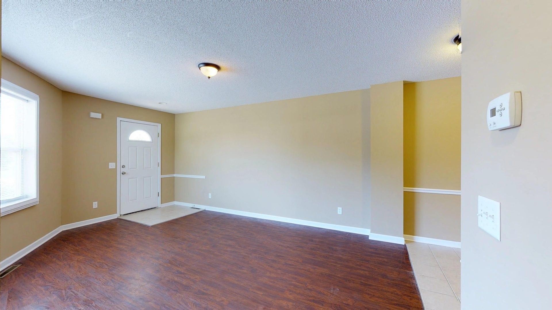 An empty living room with a brown floor and a white door.