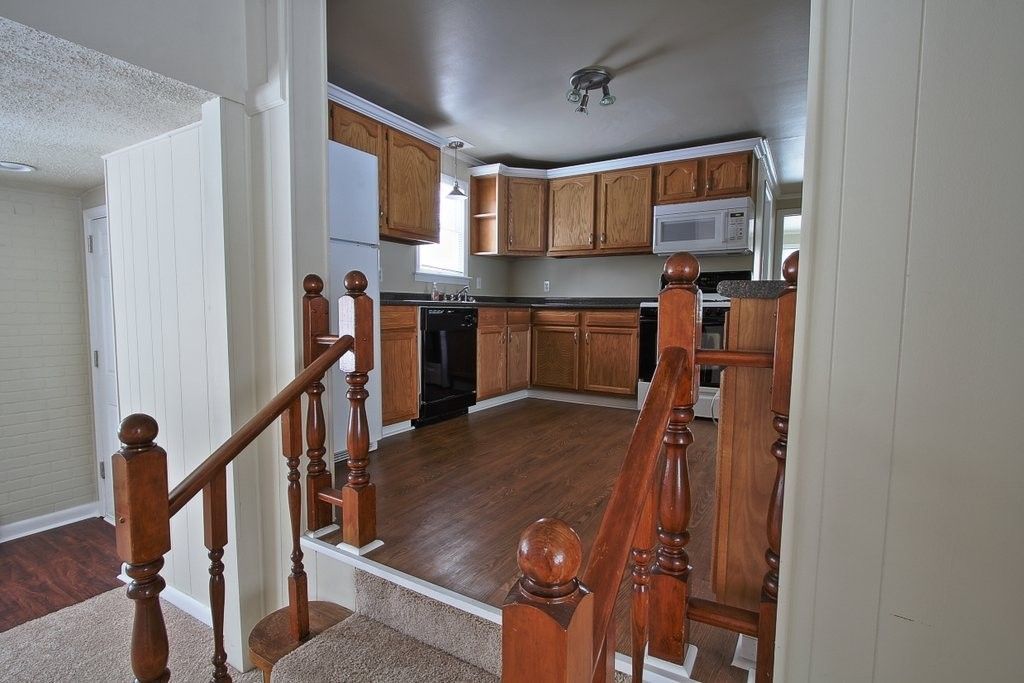 A kitchen with wooden cabinets and stairs leading up to it