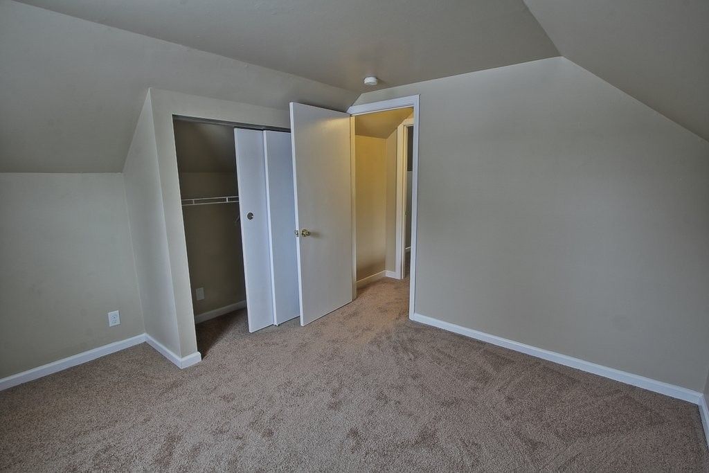 An empty bedroom with a slanted ceiling and a closet.