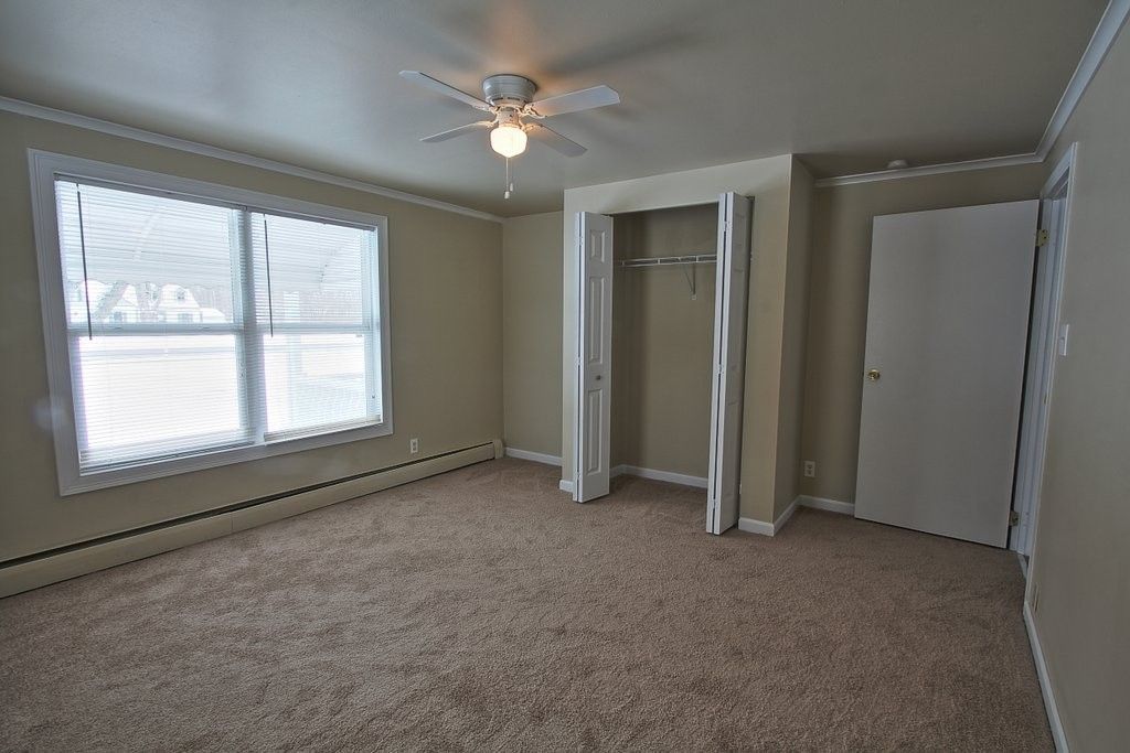 An empty bedroom with a ceiling fan and a closet