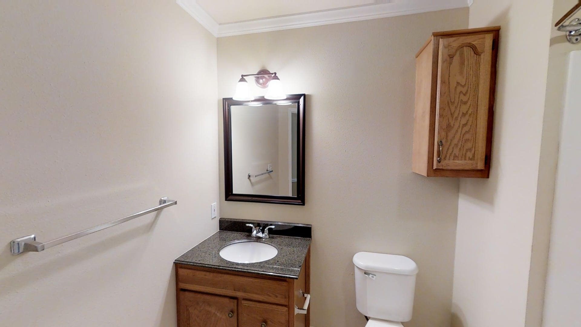 A bathroom with a sink , toilet , mirror and cabinet.
