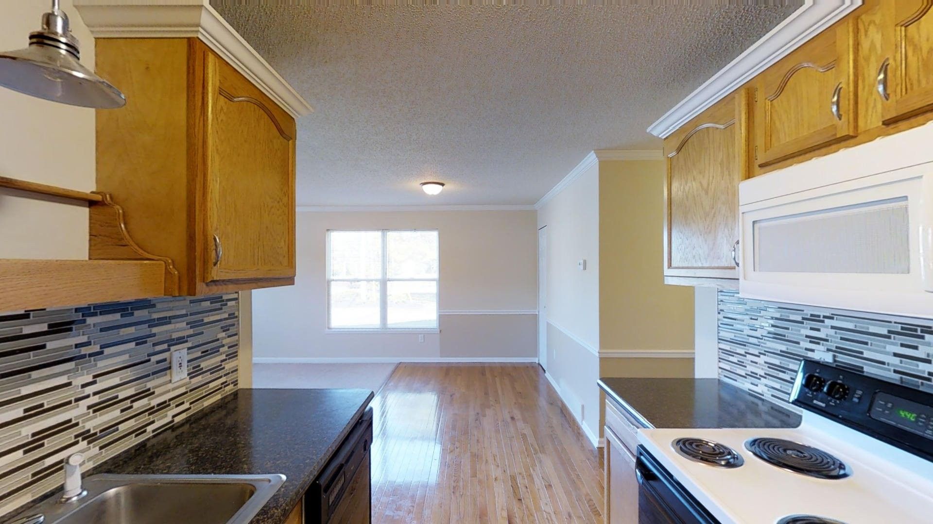 A kitchen with a stove , sink , and microwave.