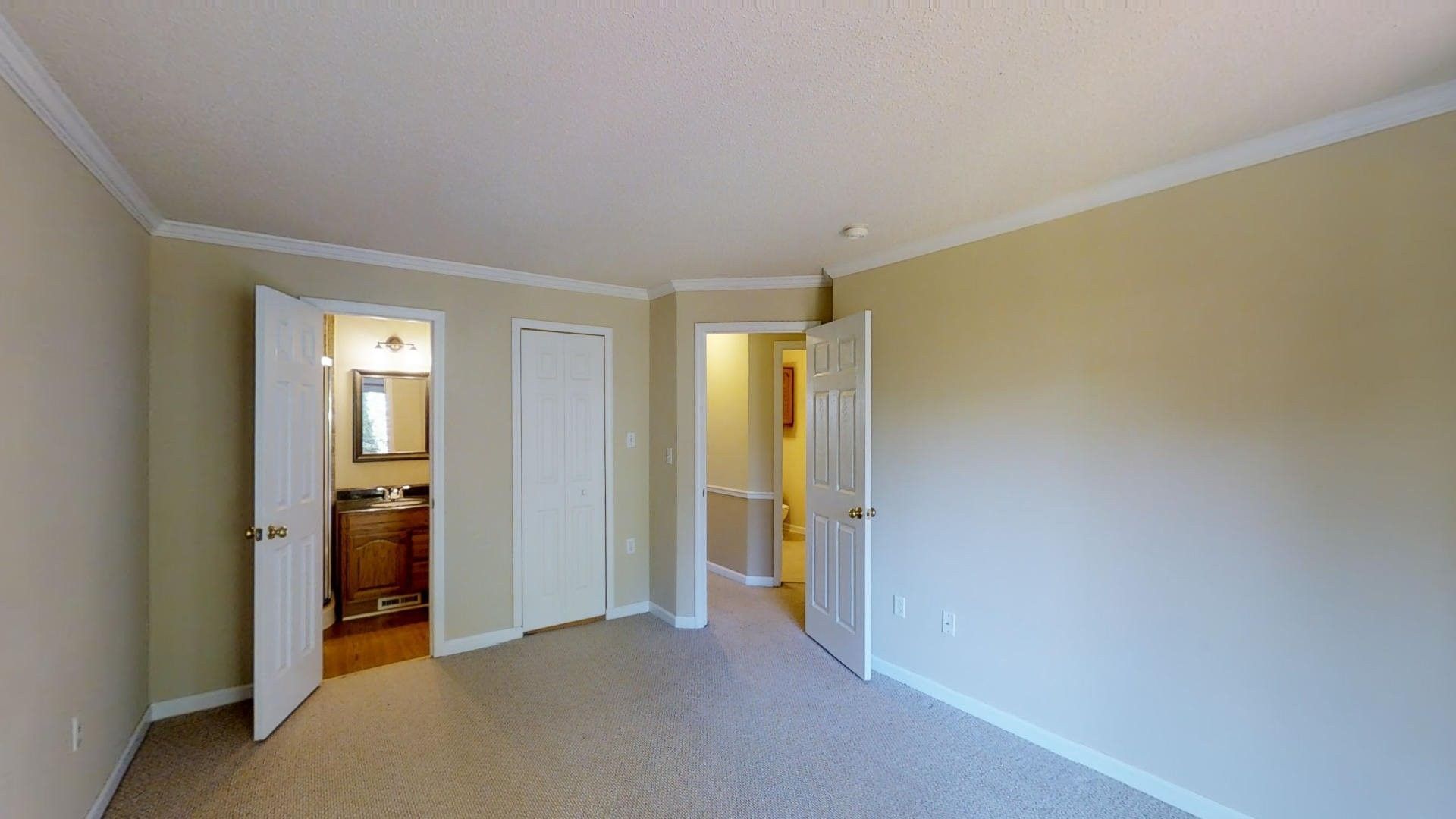 An empty bedroom with a bathroom and a sink in it.