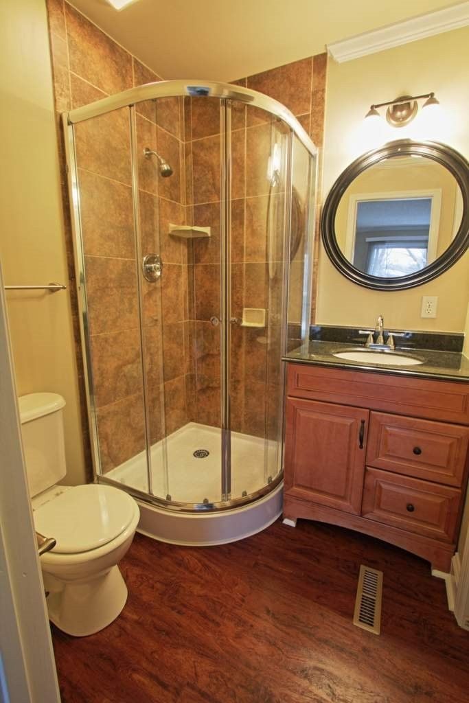 A bathroom with a toilet , sink , shower and mirror.