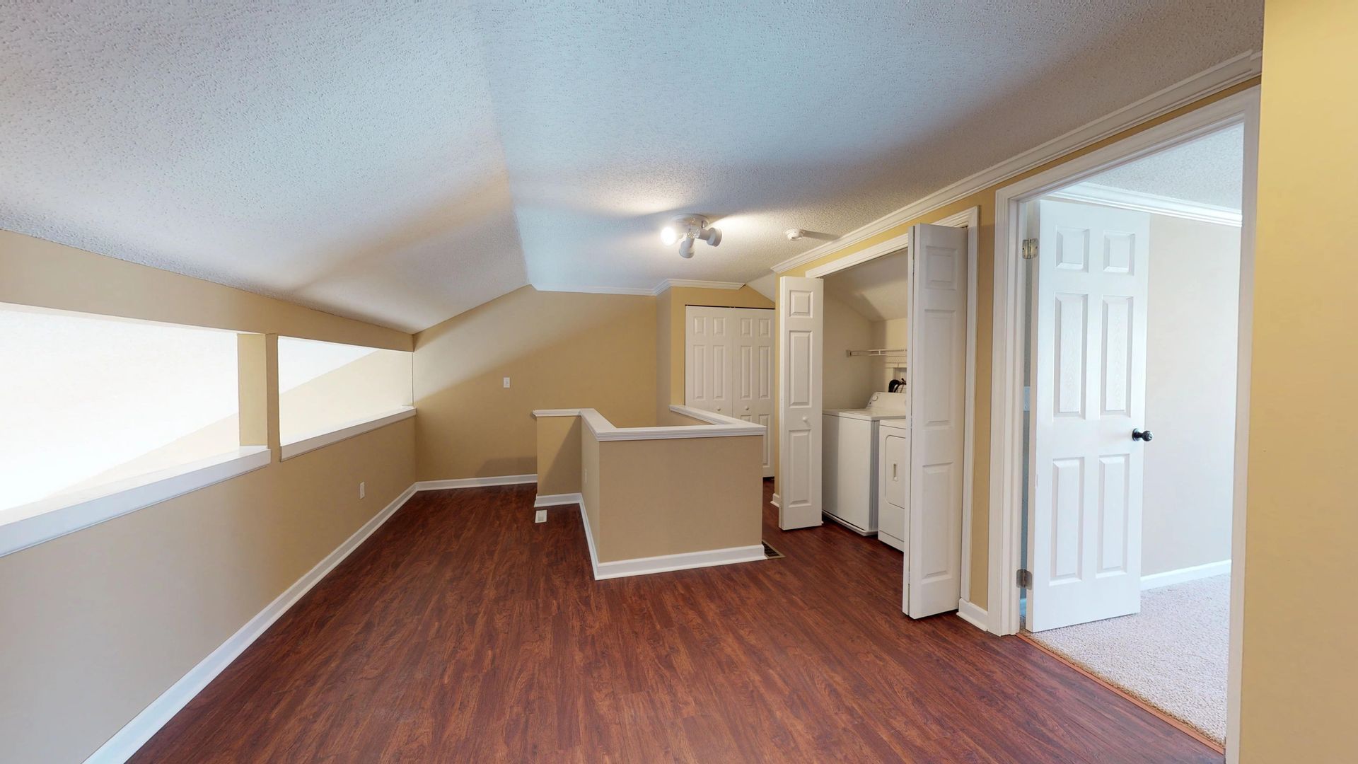 An empty room with hardwood floors and a staircase in a house.