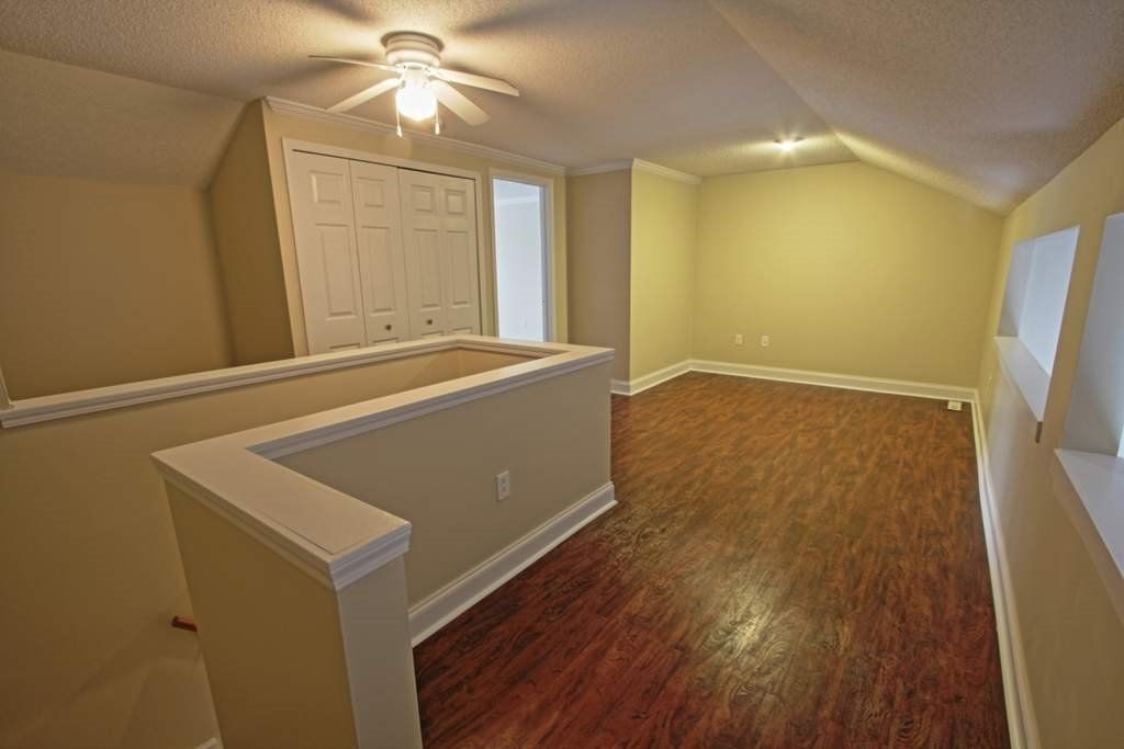 An empty living room with hardwood floors and a ceiling fan.