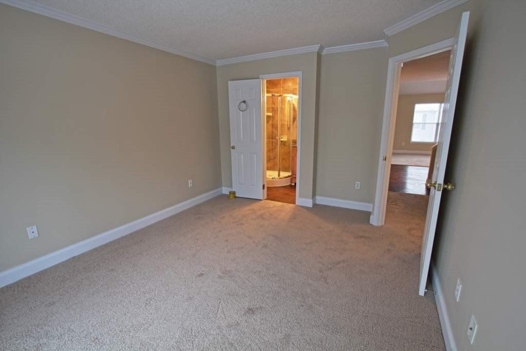 An empty bedroom with a carpeted floor and beige walls