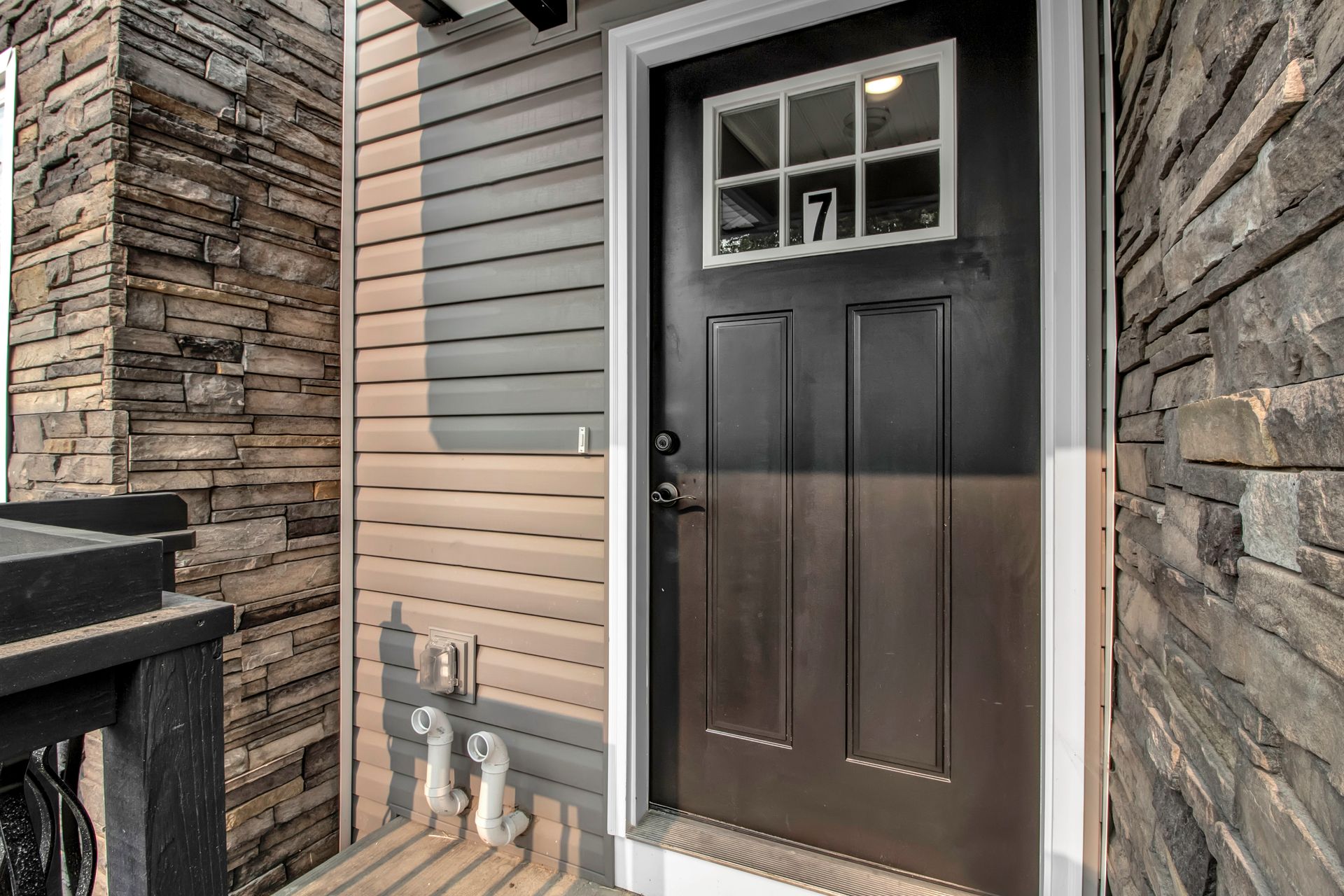The front door of a house with a stone wall and a black door.