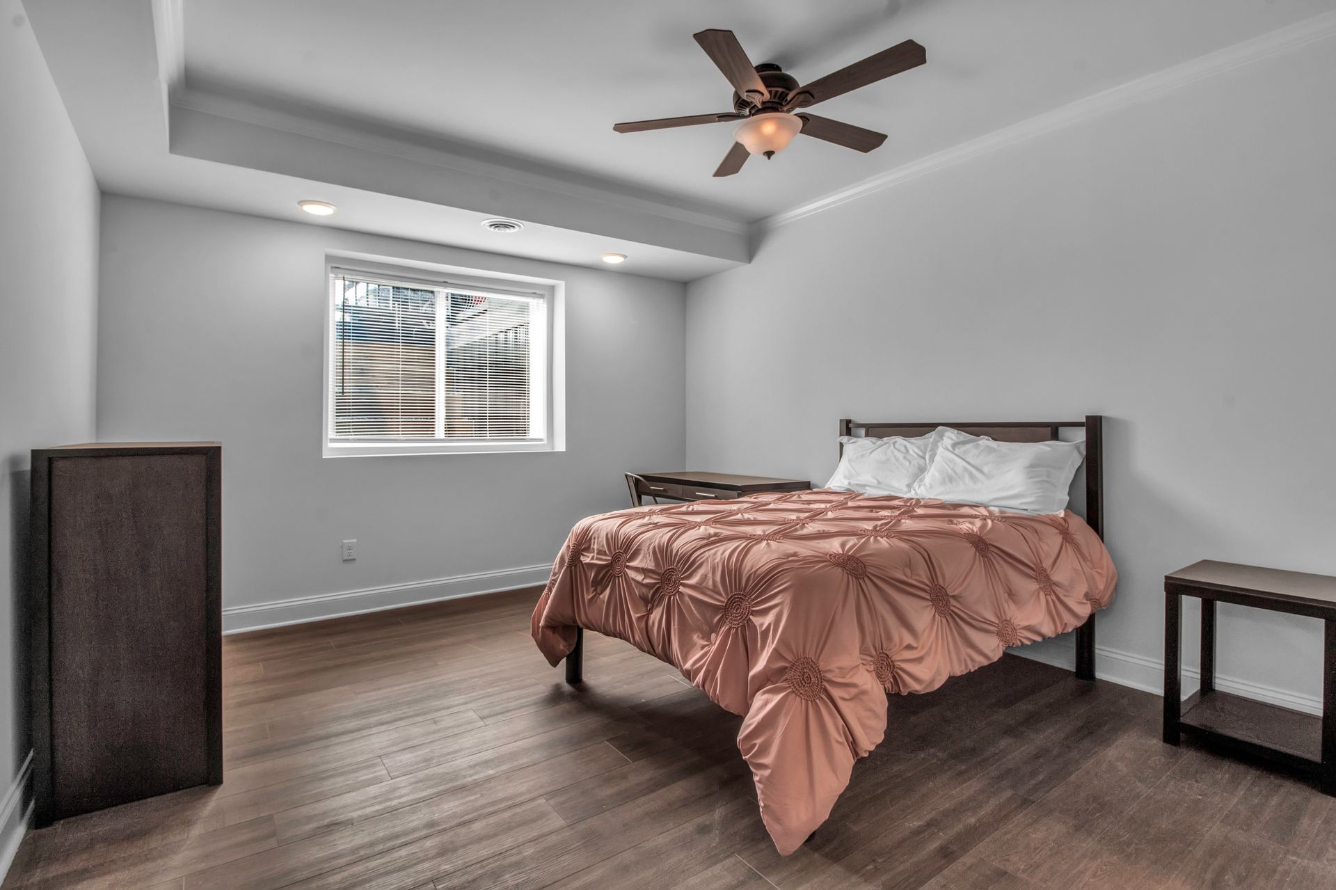 A bedroom with a bed , nightstand , dresser and ceiling fan.