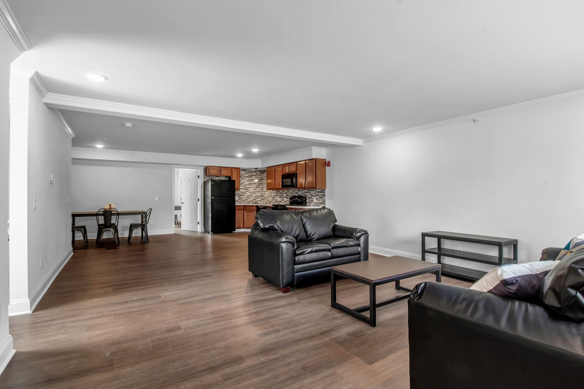 A living room with a couch , table , chairs and a kitchen.