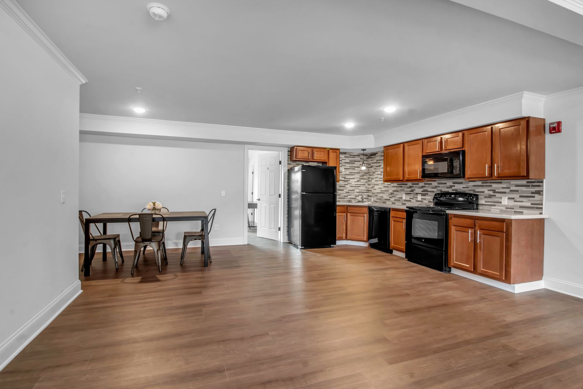 A kitchen with wooden cabinets , a black refrigerator , a stove , and a table.