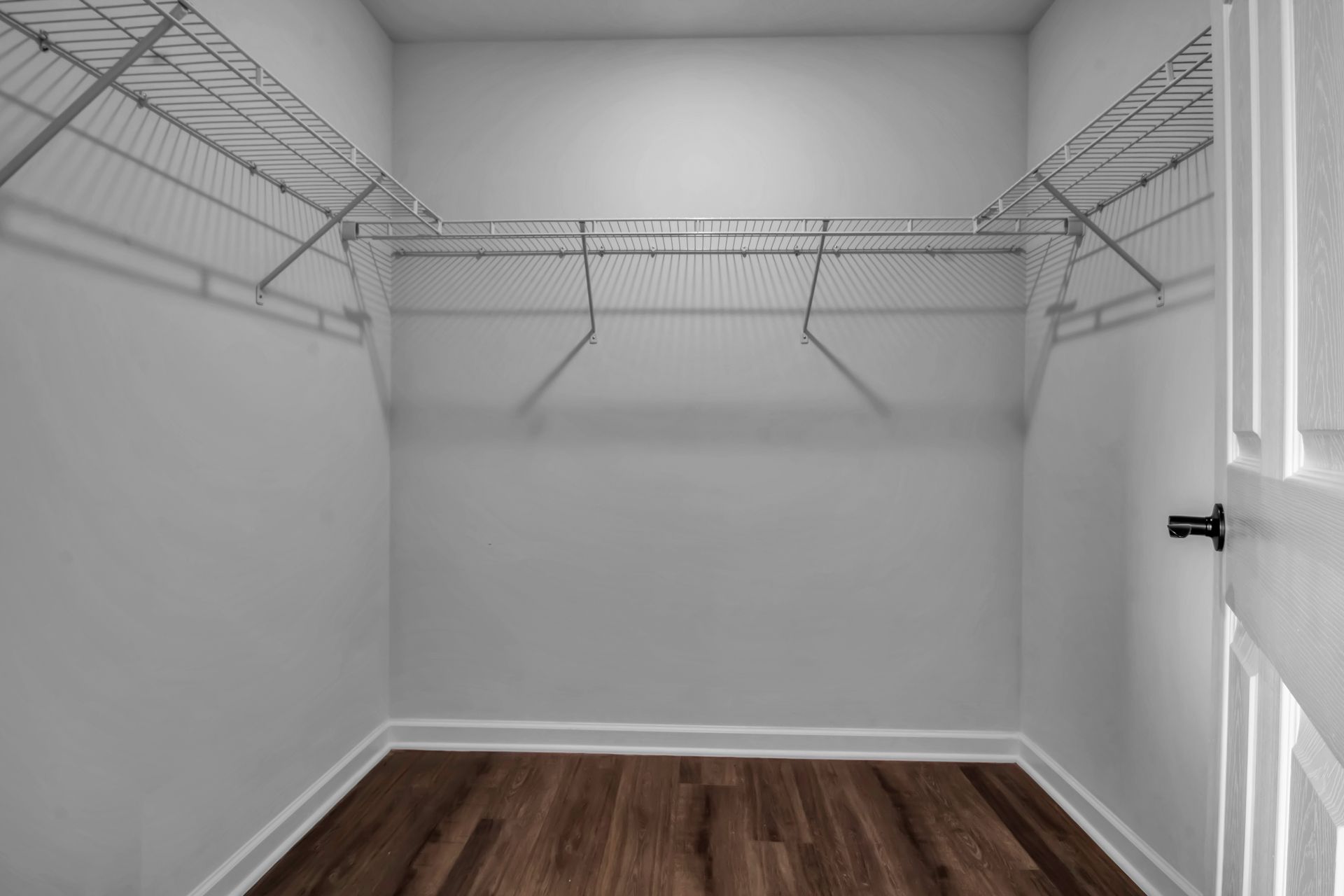 An empty walk in closet with wooden floors and wire shelves.