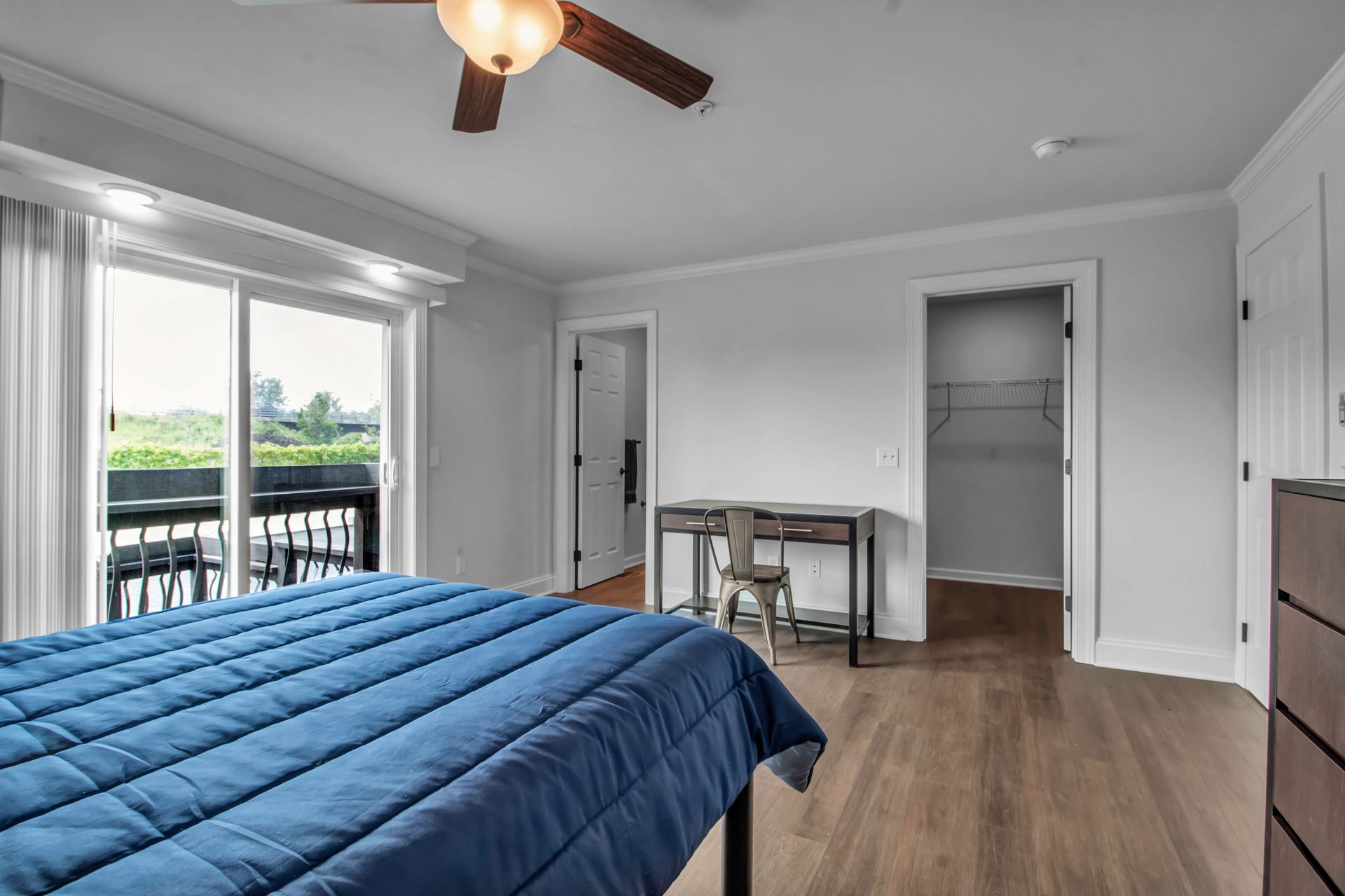 A bedroom with a bed , desk , and ceiling fan.