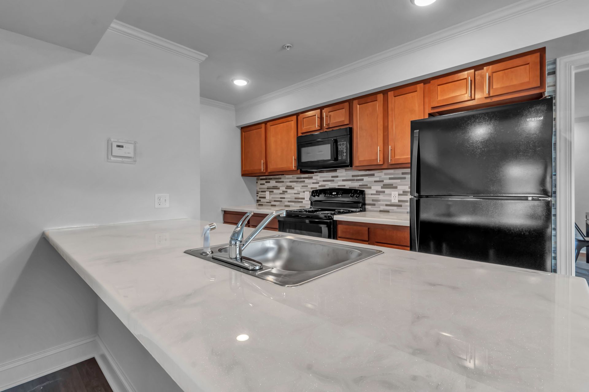 A kitchen with a sink , refrigerator , stove and microwave.