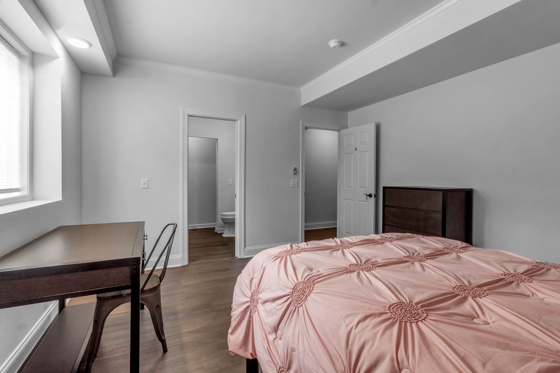 A bedroom with a bed , desk , chair and window.