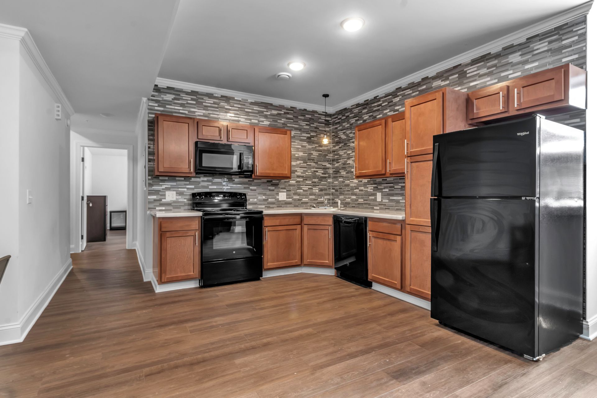A kitchen with wooden cabinets , stainless steel appliances , and a black refrigerator.