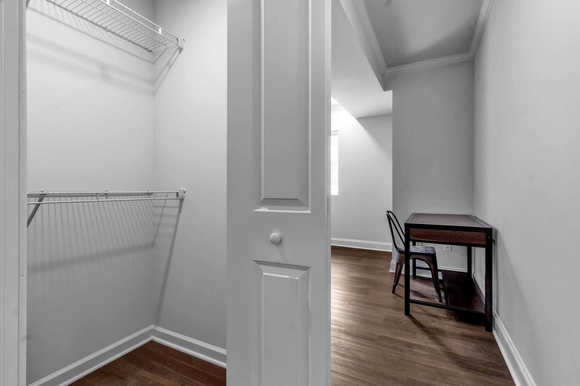 A walk in closet with a desk and chair in a bedroom.