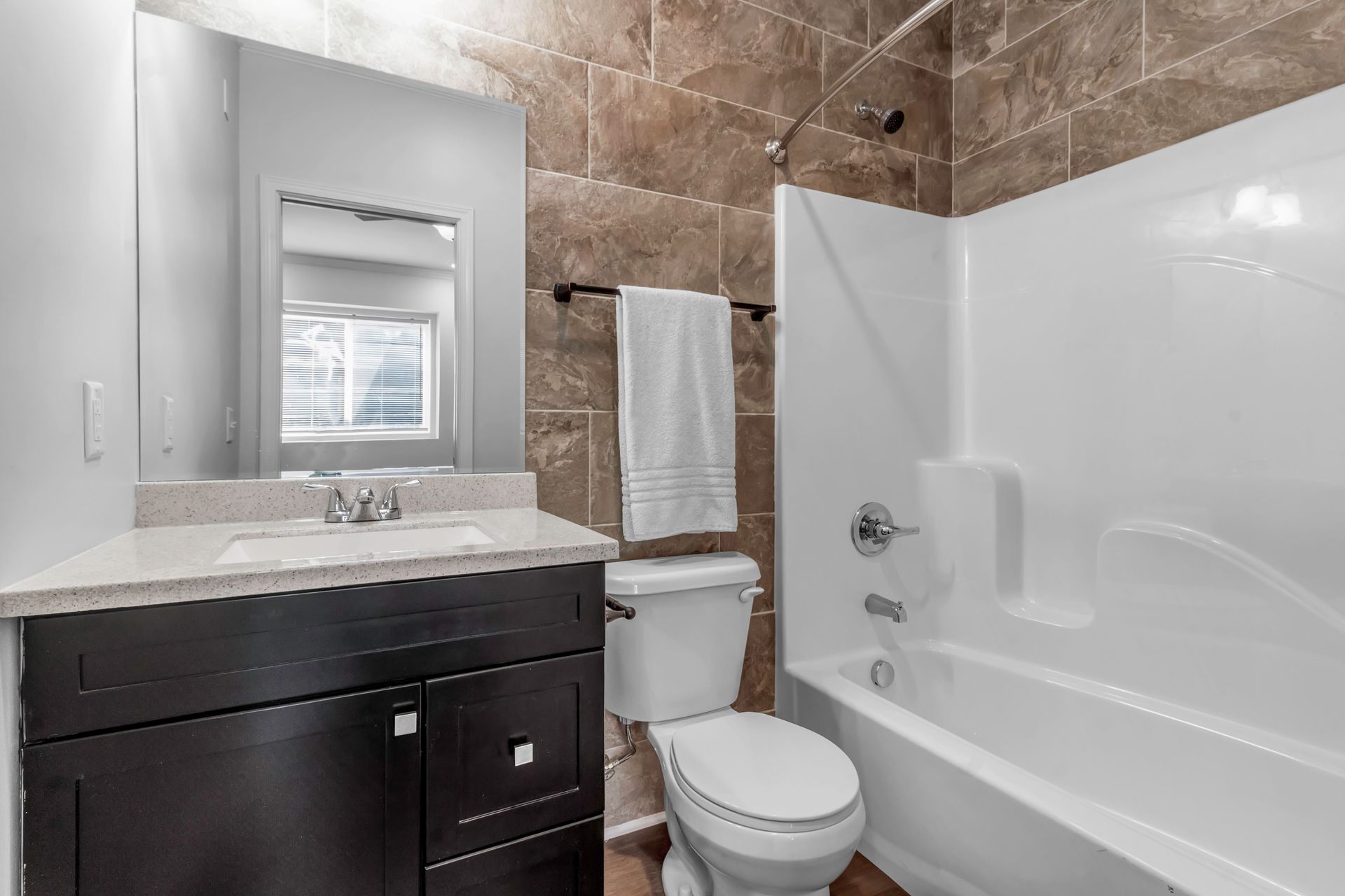 A bathroom with a toilet , sink , tub and mirror.