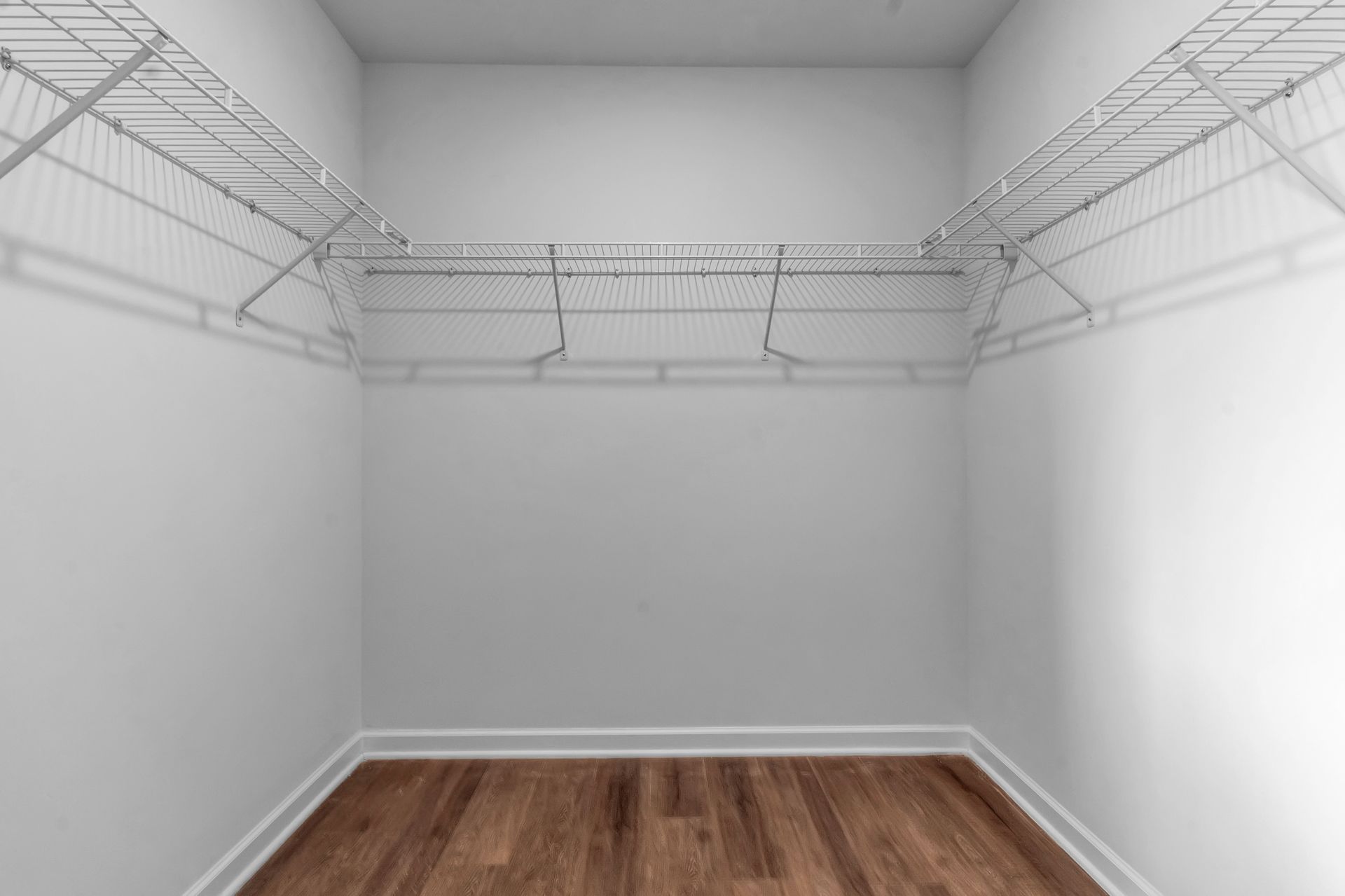 An empty walk in closet with wooden floors and wire shelves.