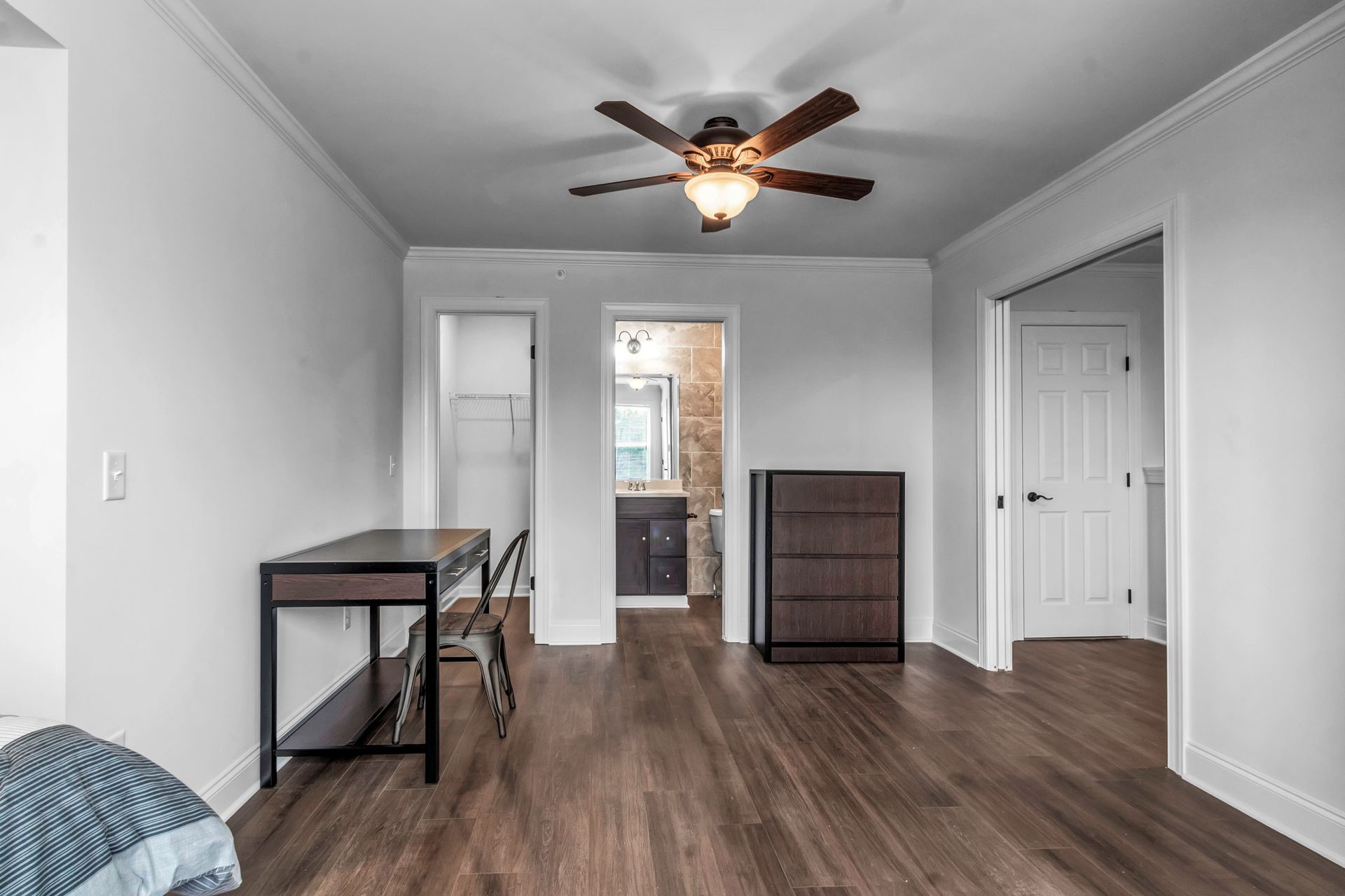 A bedroom with hardwood floors and a ceiling fan.