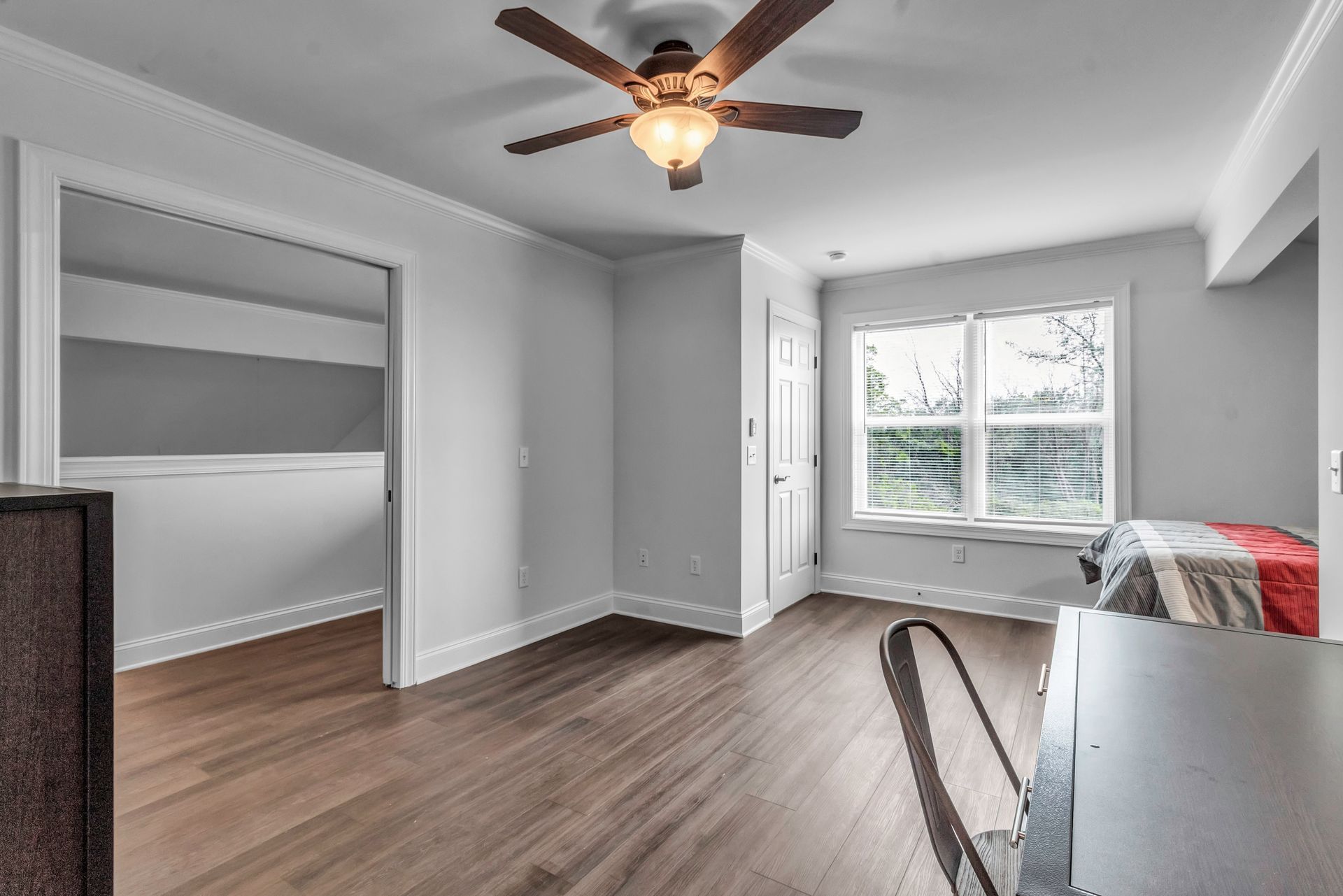 An empty room with hardwood floors and a ceiling fan.