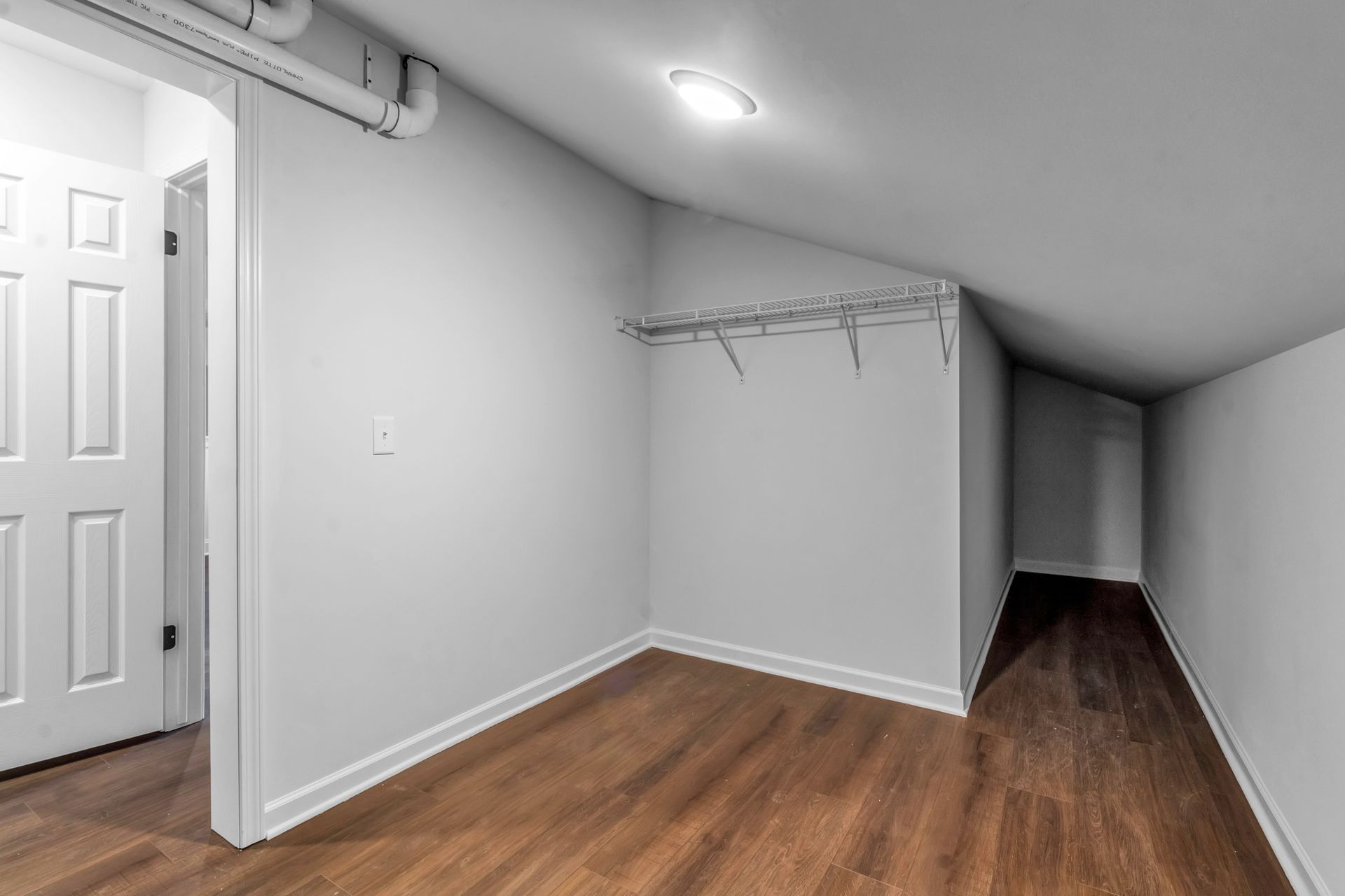 An empty room with hardwood floors and white walls.