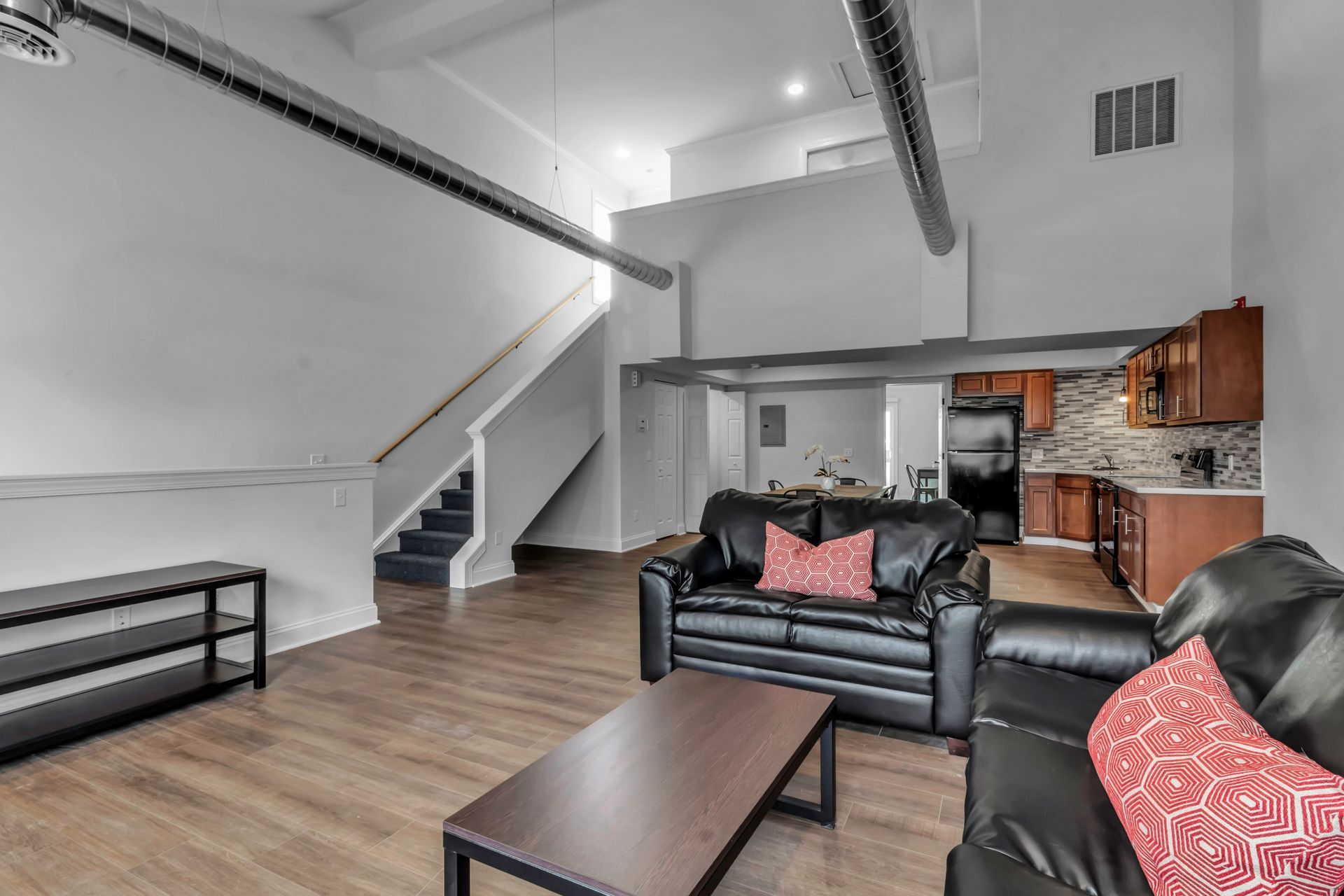 A living room with a couch , coffee table , and stairs leading to the kitchen.