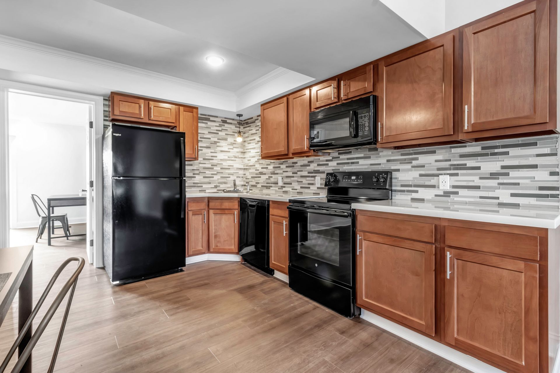 A kitchen with wooden cabinets , a black refrigerator , a stove , and a microwave.