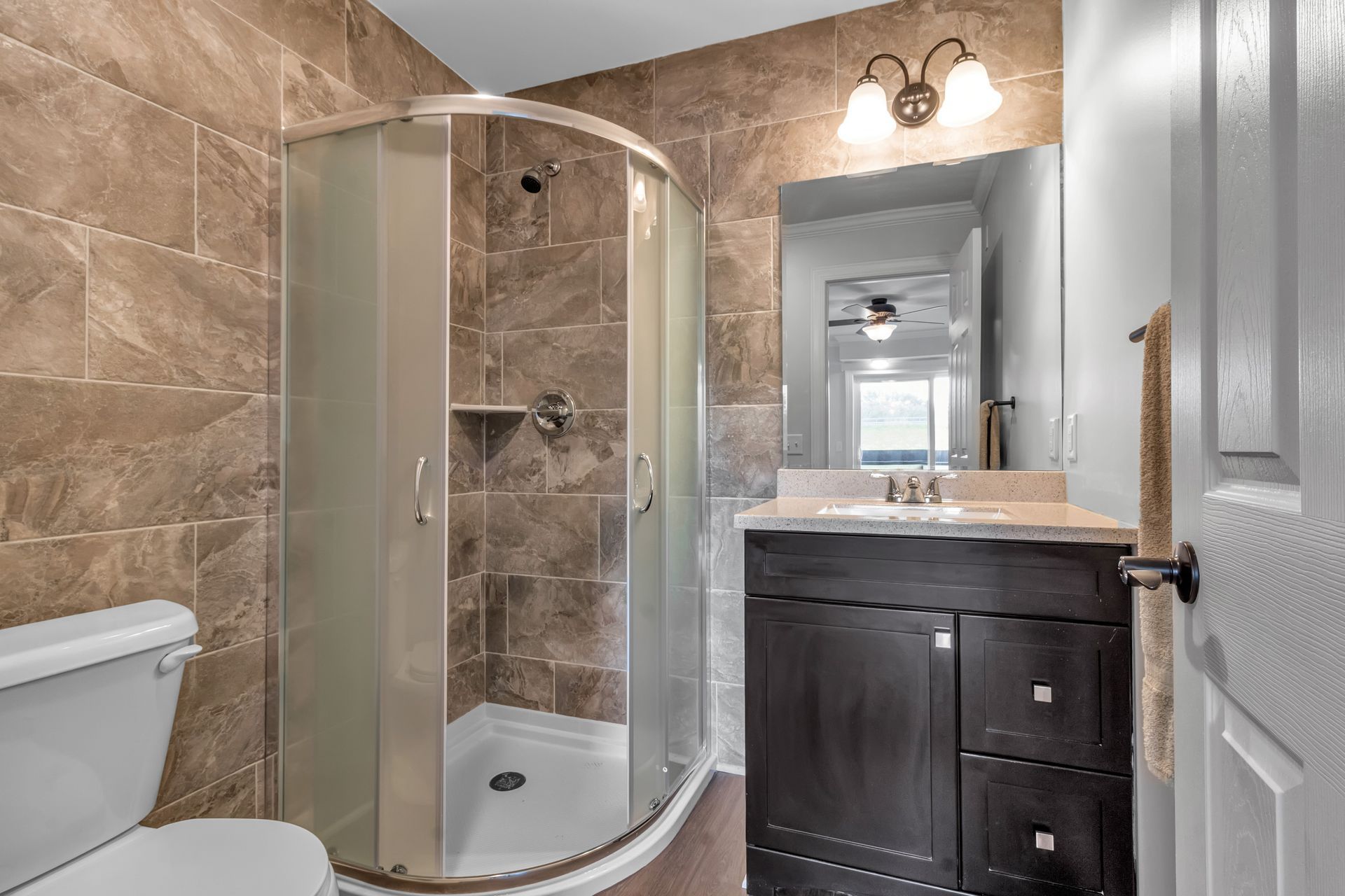 A bathroom with a toilet , sink , shower and mirror.