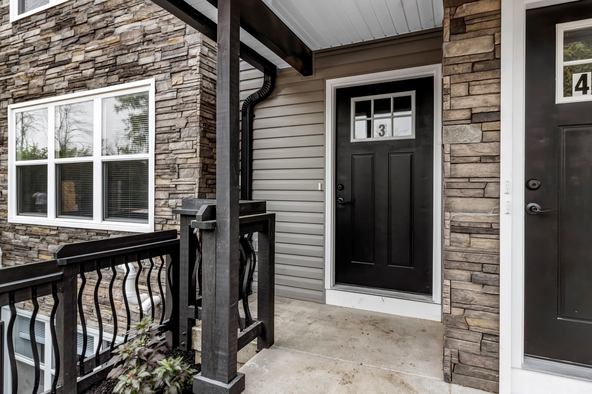 The front door of a house with a balcony and a black door.