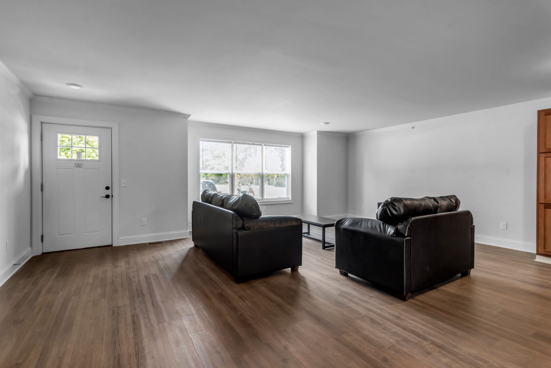 A living room with hardwood floors , two couches and a table.