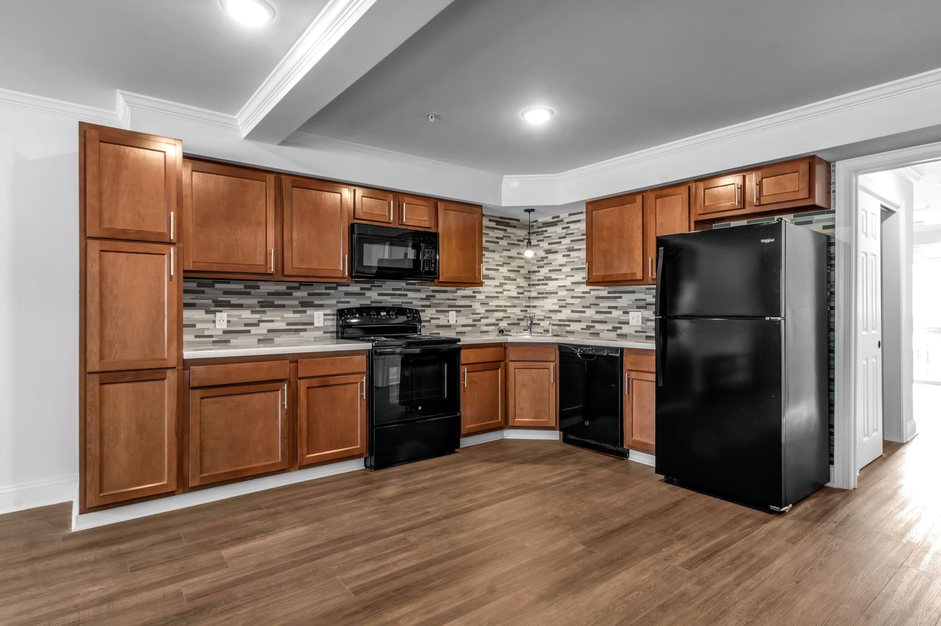 A kitchen with wooden cabinets , a black refrigerator , a stove , and a microwave.
